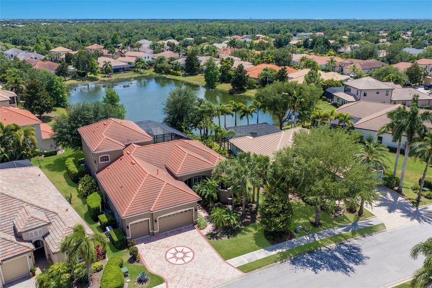 A home that lives like a private resort in the heart of Lakewood Ranch. Situated on a picturesque ¼ acre lakefront homesite in Greenbrook Village, this expansive 5-bedroom plus office and Media room, 4-bath luxury residence offers over 4,100 square feet of thoughtfully designed living space with exceptional indoor-outdoor flow and countless upgrades throughout. From the moment you arrive, the engraved driveway, mature landscaping, and dramatic evening landscape lighting create unforgettable curb appeal.
Inside, etched French doors open to soaring 12-foot ceilings, abundant natural light, tray ceiling details, and sweeping views of the pool and lake beyond. Designed for both entertaining and everyday comfort, the home features formal living and dining spaces, a spacious family room with disappearing sliders, and durable tile flooring throughout the main living areas.
The chef’s kitchen is beautifully appointed with quartz countertops, cherry wood cabinetry, newer appliances, a gas range, center island, and expansive breakfast bar ideal for gatherings large or small. The split-bedroom floor plan provides privacy for the luxurious primary suite, complete with direct lanai access, oversized walk-through closet, and a spa-inspired bath featuring dual vanities, garden tub, walk-in shower, and serene garden views from aquarium-style window. A private office or flex room, along with additional guest bedrooms and baths, complete the main level.
Upstairs, an oversized bonus room currently configured as a theater offers endless flexibility for a game room, lounge, or media retreat and is already plumbed for a future wet bar or kitchenette. Two additional bedrooms, a full bath, and a covered balcony overlook the sparkling pool and tranquil lake setting.
Outdoor living takes center stage with an impressive two-story screened lanai featuring programmable multi-color lighting, an infinity-edge pool with waterfalls and spa, shaded gathering areas, outdoor shower, and pre-plumbing for a future outdoor kitchen. The peaceful waterfront backdrop creates exceptional privacy and a true Florida lifestyle experience.
Additional upgrades include hurricane-rated windows and doors, a reinforced two-story pool cage, full-house generator, whole house water filter, tankless natural gas water heater, remote-controlled blinds, fresh exterior paint, and walkable attic storage with new 375-pound ladder access.
Perfectly positioned near Adventure Park, nature trails, playgrounds, dog parks, top-rated schools, Lakewood Ranch Main Street, UTC shopping and dining, Premier Sports Campus, golf, and the Gulf Coast’s renowned beaches, this home delivers space, luxury, and lifestyle in one remarkable offering.