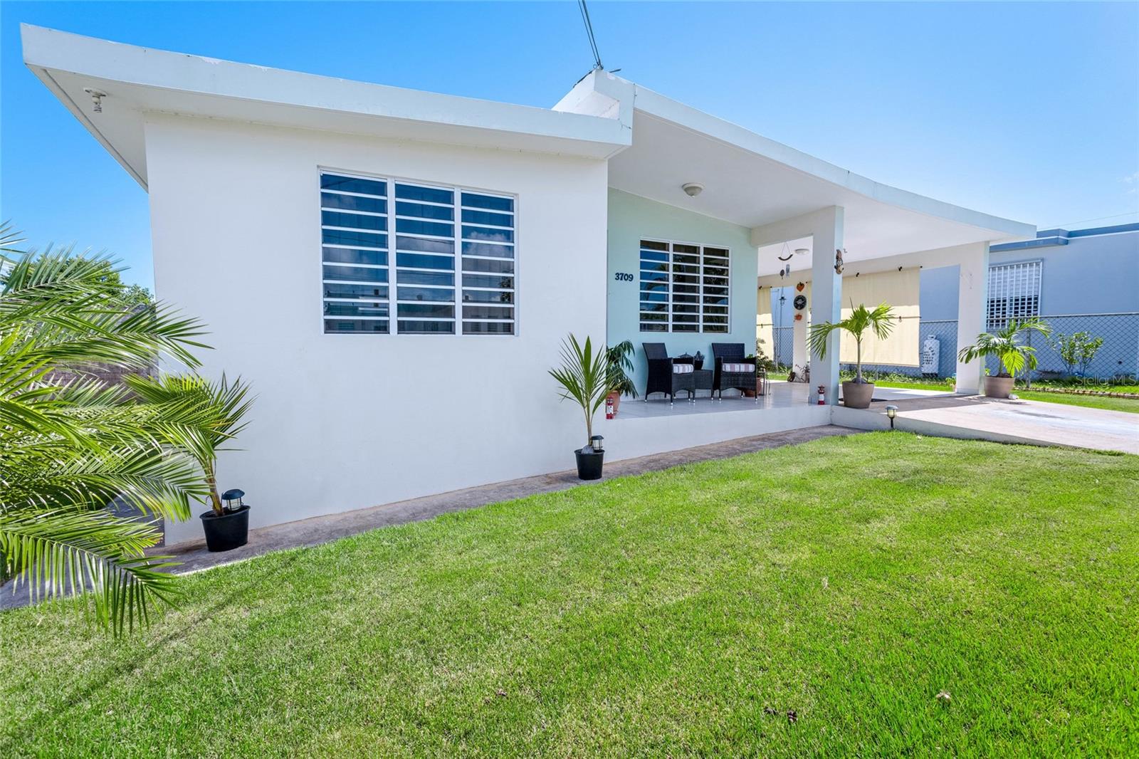 Discover a charming residence in the heart of Isabela, blending comfort, functionality, and investment potential in one of Puerto Rico’s most desirable coastal towns. The home features an open floor plan where the kitchen and living area flow seamlessly, creating a bright and welcoming environment ideal for both everyday living and entertaining. With thoughtful upgrades, including a recently sealed roof and a solar water heater, the property balances convenience with efficiency. Set on a 515 square meter lot, the residence offers 1,020 square feet of interior living space.
The layout offers three bedrooms and two bathrooms, with one bedroom designed as a versatile space that can function as a studio, office, or private suite, complete with its own bath and separate entrance—an ideal option for extended family or rental opportunities. The main bathroom is enhanced with a custom barn door and a modern, earthy design, while the rest of the home reflects a relaxed and stylish atmosphere. Outdoor spaces invite you to embrace a tropical lifestyle with a manicured lawn, shaded front porch, fruit trees, and an area ideal for gatherings, play, or simply relaxing. A metal storage shed provides added convenience, while the carport and landscaped frontage add to the home’s curb appeal.
The property enjoys an ideal setting on a dead-end street with no through traffic, yet is just minutes from Isabela’s town square and Plaza Isabela Shopping Center, home to Walmart and the island’s newest Chick-fil-A. Its location provides easy access to some of Puerto Rico’s most sought-after attractions: only fifteen minutes to Jobos Beach, known for its surf and vibrant dining scene, as well as Montones, Middles, and Teodoro beaches. The historic Guajataca Tunnel and the lively nightlife of Villa Pasquera are also nearby. For travel convenience, the home is just fifteen minutes from Aguadilla’s Rafael Hernández Airport and approximately an hour and a half from San Juan’s Luis Muñoz MarÃn International Airport.
This Isabela residence presents a rare opportunity to own a versatile and well-appointed home in Puerto Rico’s northwest coast, ideal as a primary residence, vacation retreat, or income-producing property.