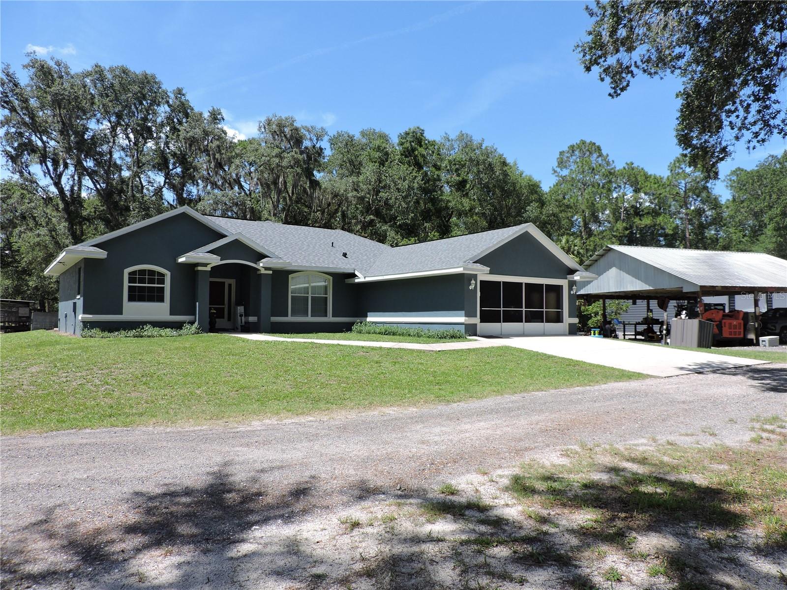 This exceptional private property spans five acres with mature oak trees, a long private driveway of millings leading to the freshly painted updated 3 bedroom 2 bath house nestled far away from the road toward the rear of the property, passing the 40 x 40 new metal barn which has 3 roll up doors, side entry door, 100 amp service, water, east bay has 8” thick concrete for future mechanic’s lift, the 36 x 36 concrete floor open carport has 3 parking spaces and workshop, all in close proximity to the home which has a two-car garage. The home has a thoughtfully designed floor plan, tile bathrooms, laundry & kitchen with real wood floors throughout the rest, upon entering the foyer you’re greeted by a spacious living room with vaulted ceiling takes you to a sliding glass door that opens to the 21 x 9 screened porch where you can sit with a cold drink or morning coffee watching the deer, turkeys, and wildlife. The master suite is a generous size bedroom with master bath equipped whirlpool tub, double vanities, a step-in shower, and spacious walk-in closets. Two additional bedrooms which share a second full bath, in house laundry room off the kitchen featuring abundant cabinetry with Corian countertops, panty, eat in bar, breakfast nook, and separate dining room. Highlights include new roof, new water heater, new exterior house paint, newer ac, insulated garage & rear porch ceiling, and RV outlet. Bring your animals, ATV, RV, boats, & toys as this property is ready for it all! Less than 4-miles away you have county owned Bull Creek Fish Camp with new coming restaurant, boat ramp, kayaking, fishing, then on your way to county owned Russell Landing boat ramp with bathrooms, picnic area, trails you pass the county owned lighted arena and Pellicer Community Center for family parties. This home is designed for peace, privacy, functionality, and is perfect for entertaining. Don’t miss out on this incredible opportunity!