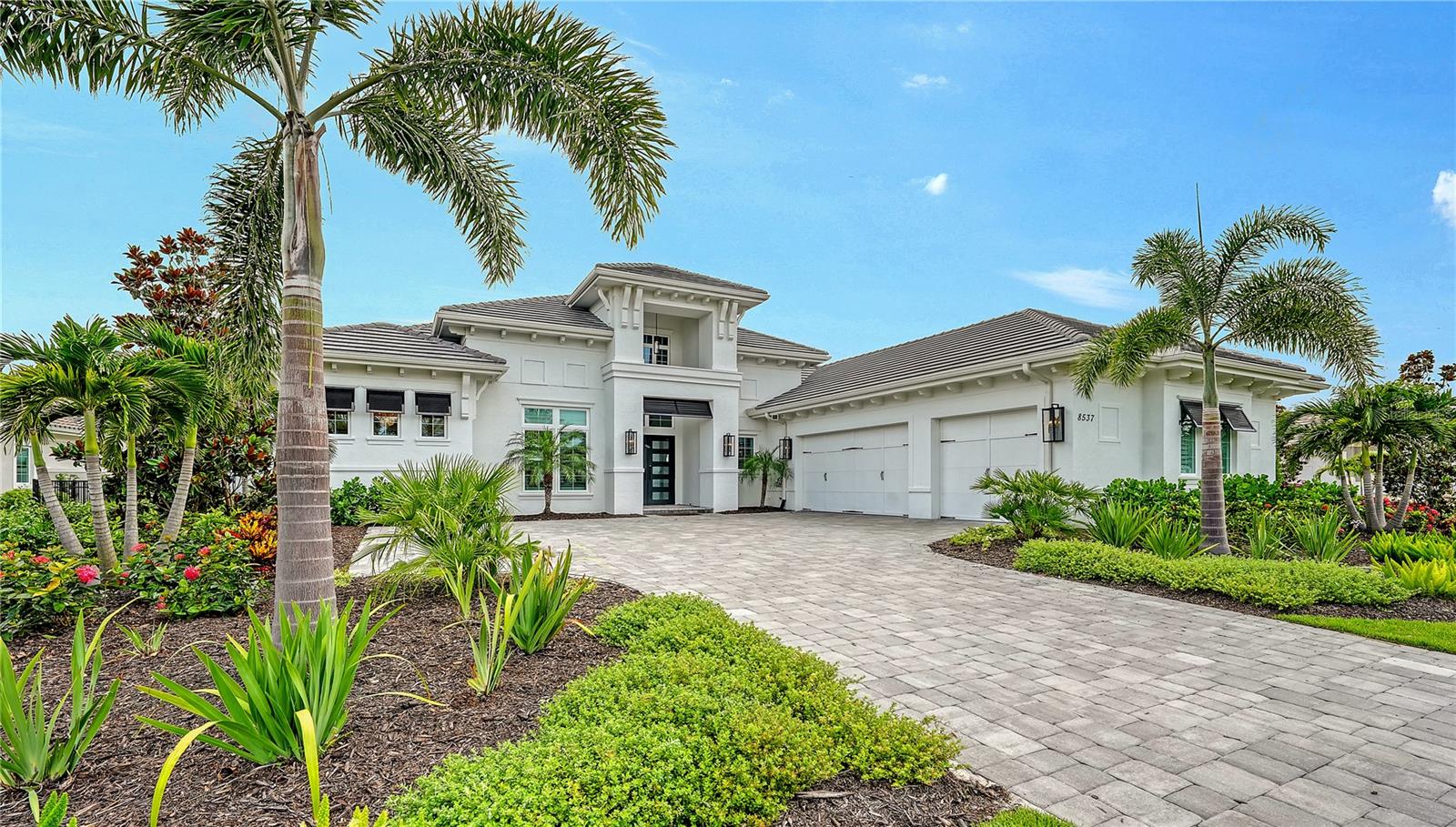 Nestled on a premier lakefront homesite within Lakewood Ranch’s exclusive enclave of The Lake Club, this impeccably furnished 2022-built residence presents a seamless blend of elegant design and resort-inspired comfort. With nearly 4,300 square feet of thoughtfully designed living space, this home features five bedrooms—including a private casita suite with morning kitchen—plus a dedicated office and five-and-a-half bathrooms. A contemporary design sets the tone, welcoming you with manicured landscaping, paver drive, and a grand double-door entry. Inside, soaring ceilings with architectural tray detailing and exposed wood beams add warmth and dimension to the open-concept layout. Wide-plank wood-grain tile runs throughout the home, complementing the neutral palette and refined finishes. Walls of impact-rated sliding glass doors floods the great room with natural light and opens to an expansive screened lanai from multiple rooms, delivering breathtaking lake views and effortless indoor-outdoor flow. The chef’s kitchen is a showpiece—anchored by a substantial quartz island with seating for six, surrounded by custom shaker-style cabinetry, under-cabinet lighting, a herringbone-patterned backsplash, and top-tier stainless steel appliances including a Wolf gas cooktop. The adjacent formal dining room, complete with a built-in buffet, wine cooler, and beverage drawers, is ideal for elevated entertaining. Designed for both function and flexibility, the home offers a guest suite just off the kitchen that doubles as a media or family room with glass sliders leading to the lanai. A separate casita provides a private retreat for guests or multigenerational living. The primary suite is a tranquil sanctuary overlooking the water, with French doors that lead to the pool deck. Dual walk-in closets feature custom built-ins, while the spa-inspired bath exudes luxury with a soaking tub, oversized walk-in shower, split vanities with quartz counters, a makeup station, and private water closet. Step outside to discover your personal paradise. The covered lanai boasts a gas fireplace, built-in TV, ceiling fan, and an outdoor kitchen equipped with a Viking grill, Zephyr commercial hood, and beverage drawers. A firepit lounge and expansive pool deck wrap around the resort-style pool with sun shelf and spillover spa—all perfectly positioned to frame sparkling lake views through a seamless panoramic screen enclosure. The Lake Club redefines luxury living with a 22,000-square-foot Grande Clubhouse offering a full-service bar and restaurant, resort pool with waterfall features, fitness center, spa services, and concierge amenities. Enjoy tennis, pickleball, basketball, and two dog parks, or join social events curated by a dedicated lifestyle director. Located within America’s top-selling multigenerational community, you’re minutes from world-class golf, upscale shopping and dining at Waterside Place and University Town Center, and a short drive to Sarasota’s cultural venues, Gulf beaches, and downtown charm. This is elevated Florida living, reimagined.