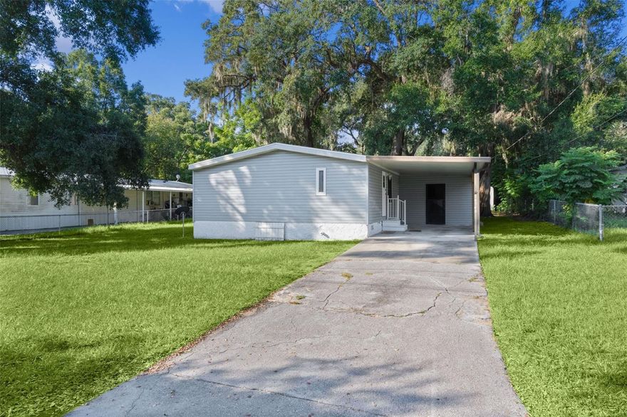Conveniently located just off US 441/27 near The Villages, this well-kept double-wide manufactured home partially furnished offers the perfect blend of accessibility and tranquility. You're minutes from shopping, dining, and medical facilities, yet far enough to enjoy peace and quiet away from the crowds. Best of all, you own the land—no lot rent and no HOA restrictions. Inside, the home features three bedrooms and two bathrooms with a spacious open floor plan, an eat-in kitchen, and a cozy fireplace in the living room. A brand-new HVAC unit has just been installed, along with new carpet and a newer roof, making this home move-in ready. The utility room off the carport includes laundry hookups and generous storage space. Outside, the large yard offers plenty of room to enjoy, plus an extra storage building at the back of the property. The home is on well and septic, with plumbing recently reworked to the septic tank. Currently vacant and easy to show—please use Showing Time to schedule your visit. As requested by the owner, kindly remove shoes or wear the provided footies during your tour, and don’t forget to leave your card and feedback.