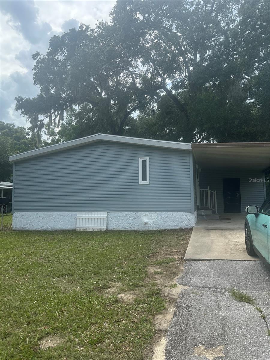 Conveniently located off 441/27 near the Villages, shopping, restaurants, medical facilities and away from the hustle and bustle of the crowds. Manufactured double wide home where you Own your own land and No HOA. This home has New HVAC. New Carpet. Newer Roof. 3-bedroom 2 bath. Eat in Kitchen, Open floor plan with Fireplace in Living room. Laundry is located in the Utility room off the carport that has ample storage area. Nice, Large yard with an extra storage building in back of the property. Home is on Septic and well. Plumbing just reworked to the septic tank. Home is vacant. Use showing time and please leave card and feedback. Also, owner has asked to remove shoes or wear footies that are there