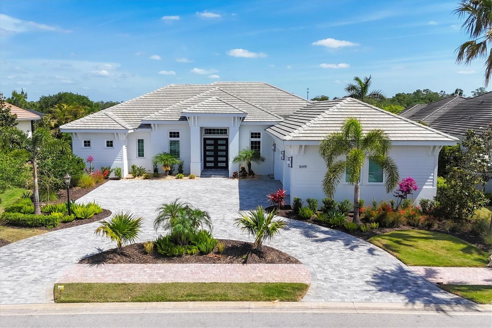 Perfectly situated on a quiet preserve in the exclusive gated enclave of Country Club East, this exceptional John Cannon residence showcases refined craftsmanship, modern luxury, and seamless indoor-outdoor living. Designed for both comfort and impact, the home features impact-rated windows and doors, a full-house generator, and an open layout that’s as functional as it is beautiful. Step through 10-foot iron and glass double doors into a dramatic great room with whitewashed European oak flooring, soaring 13-foot ceilings with chevron wood detail, and a striking natural gas fireplace framed by Basalt volcanic tile and reclaimed wood mantle. A custom Whisperkool wine wall holds up to 130 bottles, accented by a chevron Stickwood backdrop. The main foyer features a hidden closet for bags and shoes. The chef’s kitchen boasts Sub-Zero and Wolf appliances, a 6-burner range, built-in oven and microwave, quartz countertops, a prep island outfitted with pull-out drawers—two for spices—, a farmhouse sink and a standalone ice maker. A entertaining-sized island outside the kitchen features, Uline beverage and wine coolers, an additional microwave, and ample hidden storage. A spacious walk-in pantry is steps away and includes a built-in tall closet. The great room’s 10-foot sliders fold back into a disappearing corner and lead to the expansive lanai with a PebbleTec infinity-edge heated saltwater pool and spa, panoramic screen enclosure, Shell Lock pavers, and a fully outfitted summer kitchen with Alfresco grill, Trailwinds hood, True ice machine, Uline fridge, and Blanco sink. The private owner’s wing includes two walk-in closets, tray ceiling with crown molding, lanai access, and a spa-style bath with radiant heated floors and a steam shower. Two guest suites are positioned in separate wings—each with its own full bath and walk-in closet—one with a private entrance and drop zone, the other with pool bath access. Additional living spaces include a bonus room with 10-foot sliders as a second disappearing corner as well as a study/exercise room with 15-foot ceilings. The laundry room features abundant cabinet storage, designer tile, sink, and an additional 60 square feet of dedicated storage carved out behind two double doors. Adding even more value, the home is equipped with a whole-house water filtration system, designer lighting, automatic blinds, and an oversized 3-car garage. Every detail of this home has been thoughtfully curated for elevated living in one of Lakewood Ranch’s most prestigious communities.