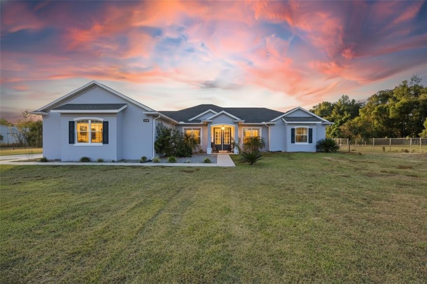 Experience refined country living at its finest in this beautifully maintained 2,400+ sq ft custom estate, perfectly positioned on 5+ pristine, fully fenced acres with an impressive automatic gated entry. From the moment you arrive, the property radiates privacy, sophistication, and pride of ownership. Inside, the home welcomes you with an open-concept design, soaring 10-ft crown-molded ceilings, and an abundance of natural light that fills the spacious living areas. The bright, airy layout is ideal for both relaxed everyday living and effortless entertaining. At the heart of the home, the chef’s kitchen shines with marble countertops, a generous sit-in island with built-in storage, double wall ovens, and premium finishes, all enhanced by built-in surround sound that carries through the main living spaces. The primary suite is a luxurious escape featuring dual walk-in closets, a 6-ft soaking tub, a beautifully tiled walk-in shower, and a dual-sink vanity designed for comfort and style. The finished garage stands out with custom cabinetry, shelving, and tiled flooring—offering exceptional storage, organization, and workspace for hobbies, vehicles, or equipment. Step outside to a true resort-style oasis. The 16x32 heated in-ground pool, spa-inspired hot tub, and expansive patio invite year-round relaxation and outdoor living. Whether you’re enjoying quiet mornings by the water or hosting weekend gatherings, this space elevates everyday life. Energy-efficient upgrades—including solar panels and a tankless water heater—provide modern convenience and long-term savings. The open acreage offers endless possibilities: bring your horses, create recreational spaces, or plan future expansions tailored to your lifestyle. All of this is ideally located just 15 minutes from downtown Ocala and under 30 minutes from the World Equestrian Center—close enough for convenience, yet far enough to enjoy the tranquility of private estate living. Seller is offering the option to purchase fully furnished, making this a rare turnkey property that effortlessly combines luxury, comfort, and unmatched privacy. Properties like this simply don’t come along often. Schedule your tour TODAY!