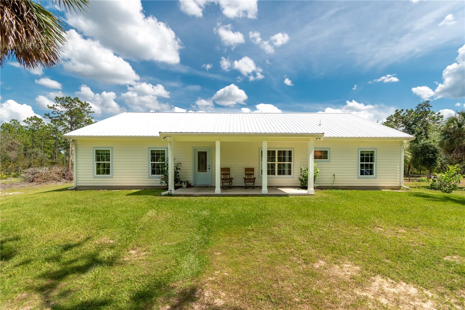 Imagine owning 12.25 secluded acres that border the Cross Florida Greenway, where wildlife abounds and nature thrives. Daily sightings of deer, turkey, and native birdlife make this private retreat one-of-a-kind. Soak in spacious and serene views from the front and back southern porches of this custom-built 2022 4BR/2BA home. Perfectly designed for rocking chairs, sweet tea, and peaceful evenings.
Inside, a spacious living room opens to a gourmet kitchen with a large island, ideal for culinary enthusiasts and effortless entertaining. High ceilings and an open floor plan provide versatile space for bedrooms, a home office, or studio use.
A 24×48 pole barn offers excellent room for equipment, storage, or future livestock. Recently cleared acreage is ready to be transformed into horse pasture, gardens, or additional recreation space.
Perfectly positioned just west of the Ocala National Forest, this property combines seclusion with access to some of North Florida’s best outdoor adventures: hunting, fishing, paddling, and exploring natural springs, rivers, and lakes. You’re only 2.9 miles to Gores Landing on the Ocklawaha River, a short drive to major grocery stores, and just 18 miles to downtown Ocala.
Whether your vision includes horses, hunting, farming, or a private retreat, this one-of-a-kind property that borders state land blends recreation, convenience, and peace — surrounded by Florida’s most treasured natural landscapes.