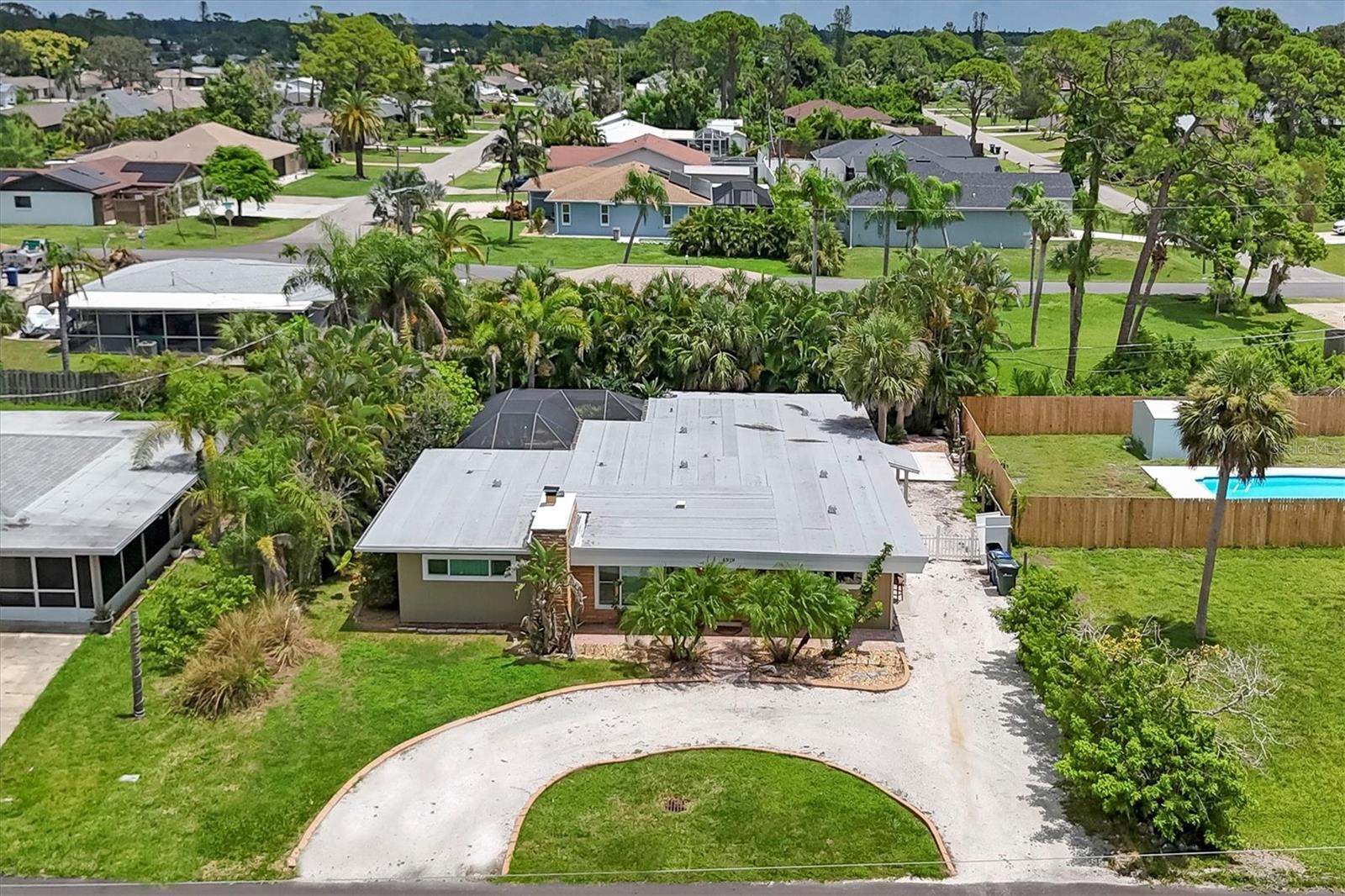 Mid-Century Modern Coastal Retreat in South Venice, welcome to 4919 Lemon Bay Drive. Conveniently located across from the Intracoastal Waterway and walking distance to the private South Venice Beach ferry, this four-bedroom, two-bath home offers an ideal coastal lifestyle. The community’s boat ramp and kayak launch are just steps away, with optional South Venice Community Association membership providing access to both amenities for approximately $200 annually. A circular crushed-shell driveway with curbing welcomes you home, offering room to park your boat or RV, along with a tropical entryway. Inside, tile flooring flows throughout, complementing the stone fireplace in the living room. The kitchen features stainless steel appliances, a breakfast bar, and tile countertops. Newer sliding and French doors fill the home with natural light, while the split-bedroom layout ensures privacy. The primary suite opens to a private seating area, creating a personal retreat. Outdoor living includes several seating areas, an oversized screened lanai finished with pavers, and landscaped grounds. Updates include an updated guest bath, newer septic, and two-zone AC installed in 2024. Enjoy nearby Shamrock Park with tennis, playground, and nature trails, or bike the Venetian Waterway to Sarasota via the Legacy Trail. With no special deed restrictions, pet-friendly policies, and excellent rental potential, this South Venice home combines location, lifestyle, and flexibility. Excellent rental opportunity and one of the largest homes in South Venice in this price range. NO HOA.