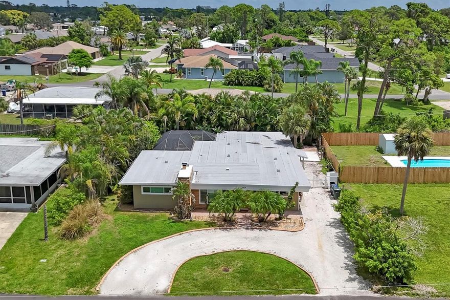 Mid-Century modern coastal retreat in South Venice, welcome to 4919 Lemon Bay Drive. Conveniently across from the Intracoastal Waterway and short distance to the private South Venice Beach ferry, this four-bedroom, two-bath home offers an ideal coastal lifestyle. The community’s boat ramp and kayak launch are just a short distance away, with optional South Venice Community Association membership providing access to both amenities for approximately $200 annually. A circular crushed-shell driveway with curbing welcomes you home, offering room to park your boat or RV, along with a tropical entryway. Inside, tile flooring flows throughout, complementing the stone fireplace in the living room. The kitchen features stainless steel appliances, a breakfast bar and tile countertops. Newer sliding and French doors fill the home with natural light, while the split-bedroom layout ensures privacy. The primary suite opens to a private seating area, creating a personal retreat. Outdoor living includes several seating areas, an oversized screened lanai finished with pavers, and landscaped grounds. Updates include an updated guest bath, newer septic, and two-zone air-conditioner installed in 2024. Enjoy nearby Shamrock Park with tennis, playground, and nature trails, or bike the Venetian Waterway to Sarasota via the Legacy Trail. With no special deed restrictions, pet-friendly policies and excellent rental potential, this South Venice home combines location, lifestyle and flexibility. Excellent rental opportunity and one of the largest homes in South Venice in this price range. No HOA.