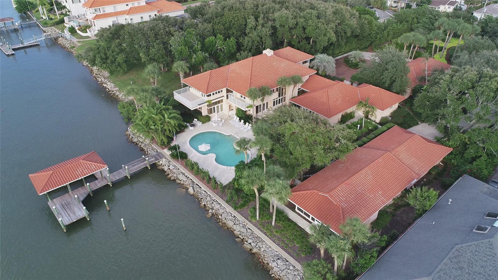 This island beachside property consists of two adjoining but separately deeded physical addresses located at 602 North Peninsula Drive and 520 North Indian River Road with access from Due East Avenue in beautiful New Smyrna Beach. Both properties are situated upon an approximately 1.2 acre parcel of land that is wooded and professionally landscaped, providing secluded privacy and direct deep-water river access to the ICW just beyond the 160 LF fully rip-rapped seawall that protects the entire property’s western waterfront edge. A beautiful 6,842 SF main home with a separate 594 SF detached pool cabana, by architect Will Jerome Miller, whose design features have allowed for exceptional scenic vistas and unobstructed views of the ICW. Windows and doors throughout the home are designed and manufactured by Pella with nicely finished treatments. Large gourmet kitchen with an expansive walk-in pantry, large living room, sitting area with a large fireplace, and 4 large bedrooms with 5 bathrooms. The guest, master, and pool suite bathrooms are adorned in classic marble design by Terry Fuqua Marble. The home encompasses custom mahogany cabinetry by Austrian craftsman Ziggy Bauer with multiple storage areas and closet space at every turn. The 2nd floor consists of approximately 2000 SF master suite with a near 180-degree view of the Intracoastal, separate private study/library and outdoor deck access, bathroom, walk in closet, a “SteamMist” steam room and shower area along with a gym overlooking the front garden. Over-sized 3 car garage contains a 100Amp Tesla charging station, workshop area with plenty of storage. Patio pool deck area is finished with a wet bar and large kidney shaped pool with spill-over spa and direct dock access to a covered 30LF by 18LF boathouse with Monier tile roof covering, fully equipped with a motorized lift system. Additionally, there are two Ace Power Hoist lifting davits upon the dock where there is deep water at the dock fronting the ICW. ;Water: City