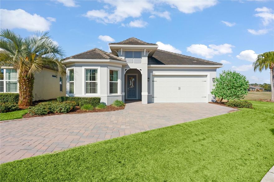 Presenting the builder’s showcase home, featuring the very best of the Four Seasons at Orlando 55+ community.  This former model is perched along hole #17 (par 3) of the Mystic Dunes Golf Course and stands supreme for its long list of upgrades and has been barely lived in. This Dominica model features 3 bedrooms (or 2 bedrooms plus den), custom-built wine bar, spectacular chef’s kitchen with giant island, gas cooktop, GE Profile oven and Advantium oven/microwave, glass tile backsplash, and custom cabinetry.  The owner’s suite offers a sanctuary of its own with bright windows, porch entry door, tray ceiling, double vanities, and walk in glass-framed shower with multiple-headed jets. Collapsing sliding glass doors open to reveal a brick paver patio with gazebo, gas fire pit, fully fenced yard, and an unobstructed view of the golf course.  Plumbing is already in place to create a summer kitchen of your dreams.  This home is one of the few available homes featuring longer lasting and highly upgraded luxury tile roofing vs shingles. Plus, a three-car tandem parking garage, with a just-completed and beautiful concrete flooring coating. Four Seasons is a 55+ resort-style community offering 24-hour guarded gated access, a 13,000 square foot clubhouse, two in-ground pools, hot tub, and fitness center, plus tennis, pickleball, and bocce ball courts. Enjoy the carefree lifestyle as all exterior landscaping is included in the HOA fees. Located just minutes from Walt Disney World® and all of Central Florida’s famed attractions. (Note: Exterior & community aerial photos show damage from the recent hard freeze in the area; green and lush landscaping will return very soon!)