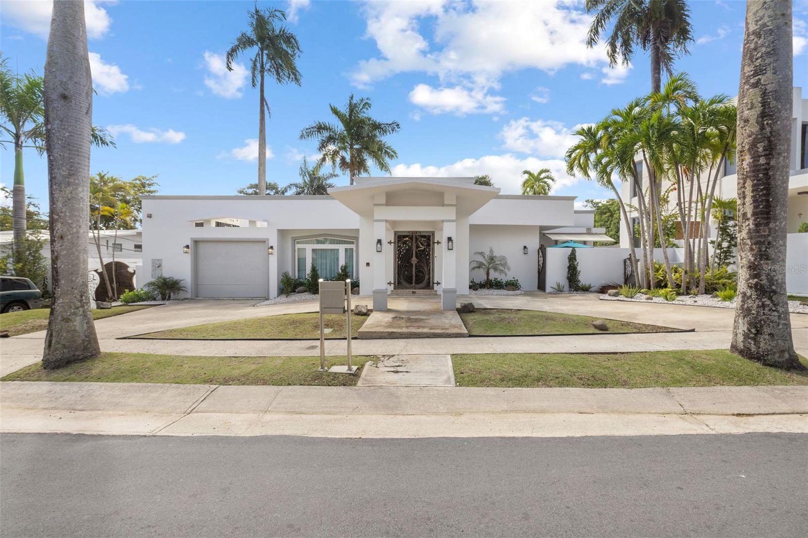 Situated in the heart of Guaynabo, nestled in the exclusive enclave of Garden Hills Norte this elegant home boasts five bedrooms,4 bathrooms, formal areas and great family/entertaining spaces. Spanning approximately 3,859 sq ft on a lot of 971 meters this spacious home welcomes you with elegant spaces designed to impress and enjoy. On the entrance floor you are greeted by a lovely foyer, formal living and dinning room, kitchen with eat in area, laundry room and a bonus champagne room which opens up to a private terrace. The grand primary bedroom is on the second floor and opens up to a large terrace. It features a walk in closet with mahogany built ins and a large bathroom. Also on the second floor are two additional bedrooms. The lower level of the home is the family area, which includes a very large family room with two sitting areas, a beautiful bar area, and two bedrooms which are used as an office and gym. This area opens up to the terrace and the pool area.
The home includes a 30 kw generator, 36 solar panels and two Tesla batteries