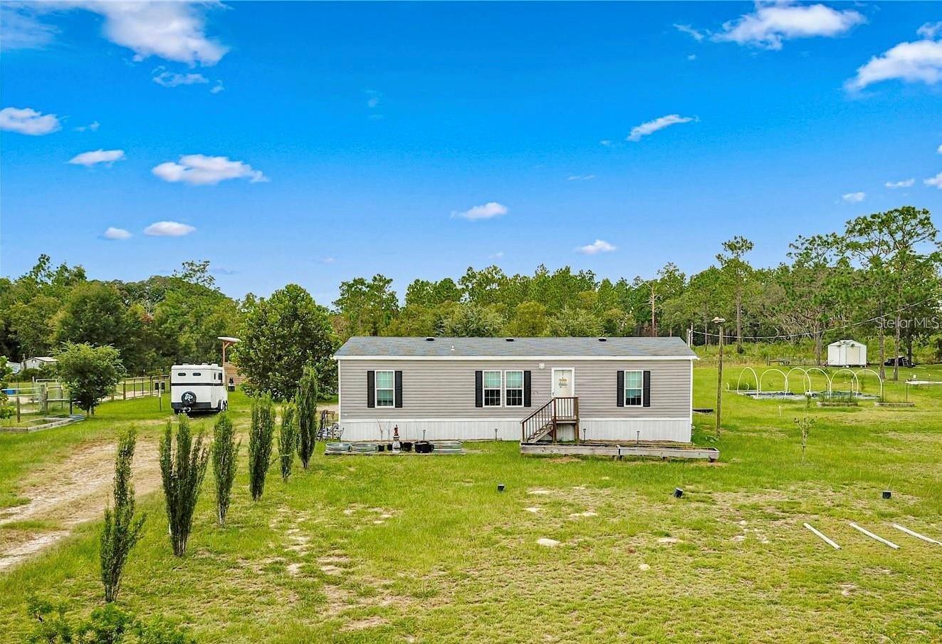 Step into this meticulously cared-for 2019 home that feels like new but comes with all the upgrades and charm you’ve been looking for. Nestled on 2 beautifully fully fenced-in acres this 3-bedroom, 2-bath home offers 1,296 Sqft of thoughtfully designed living space with a split floor plan that provides privacy and functionality. Galley kitchen featuring plenty of cabinet and counter space, perfect for preparing meals.Off the living room is the spacious primary bedroom, offering a en-suite bathroom and walk-in closet with ample storage. The additional bedrooms are equally comfortable, making this home perfect for families or those in need of extra space. Sliding glass doors lead to an expansive screened-in porch, where you can enjoy the peaceful surroundings or your morning coffee. Outside, the two-car carport and storage shed provide ample space for vehicles, tools and equipment. The property is fully fenced and divided into three pastures complete with a run-in shed and a chicken coop, making it ideal for horses, goats, chickens or other farm animals. Raised flowerbeds provide an excellent space for gardening or homesteading enthusiasts.Located only 30-miles from the World Equestrian Center, Ocala, 8-miles from the Goethe State Forest and 18-miles from HITS. This property offers the freedom of No HOA or Deed Restrictions, giving you the flexibility to truly make it your own. Schedule your private showing today and discover all the features this mini-farm has to offer!