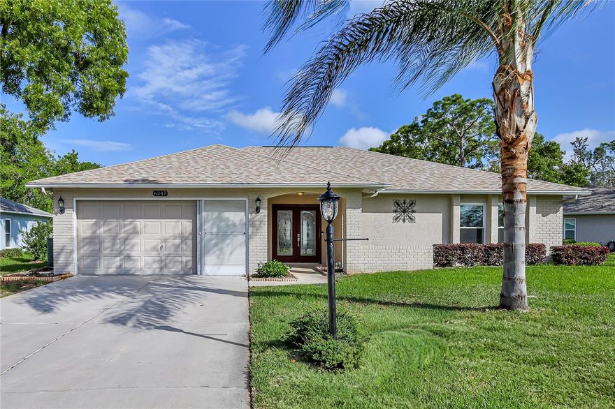 Welcome to an absolutely charming, well-maintained home offering a desirable split floor plan with 2 bedrooms, 2 bathrooms, and a 2-car garage, all situated on a spacious corner lot with irrigation. Enter through double doors into the formal living room, featuring beautiful luxury vinyl plank flooring, a ceiling fan, chair rail detailing, and a solar tube that fills the space with natural light. The guest wing is privately located and includes a front-facing bedroom with a large closet, along with a full bathroom featuring a tub and shower combination. The hallway offers two additional closets for ample storage.
The kitchen has been tastefully updated with granite countertops, wood cabinetry, pull-out pantry shelving, drawer storage, a stainless sink, and a window overlooking the yard--perfect for both functionality and charm. The formal dining room includes a built-in dry bar, ceiling fan, and opens seamlessly to the enclosed lanai.
You'll love the expansive enclosed lanai with vaulted ceilings, transom windows, and windows all around, creating a bright and inviting space for relaxing or entertaining. A door leads out to a brick paver patio, extending your outdoor living options.
The main bedroom suite features a large walk-in closet, ceiling fan, and French doors that open to the lanai. The en-suite bathroom has been updated with a walk-in shower, granite-topped vanity, and a new toilet with bidet.
Additional highlights include new windows 2015, roof 2024, HVAC system (2010), laundry area with sink in the garage, and overall pride of ownership throughout.
Timber Pines is an award winning, guard-gated, 55+, deed-restricted community offering resort-style lifestyle: three 18-hole golf courses, a 9-hole pitch & putt, tennis, 12 pickleball courts, two community swimming pools, country club restaurant and bar, fitness center, billiards, performing arts, and over 100 social clubs and activities. With major updates already completed and a layout designed for everyday living and entertaining, this home is move-in ready.