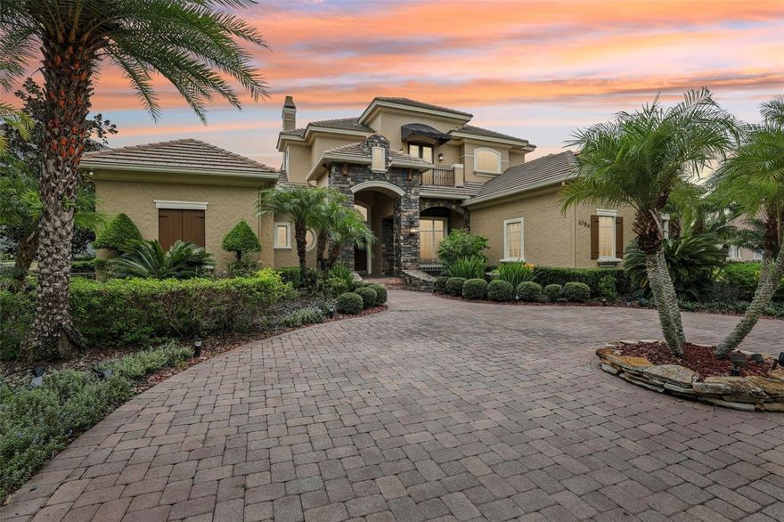 One or more photo(s) has been virtually staged. Experience breathtaking sunsets from this magnificent custom Marklen home. Perfectly situated on Lake Irish, the property boasts stunning curb appeal with lush landscaping, colorful flowers, and a circular brick-paved driveway. Step inside to soaring ceilings, arched doorways, lighted niches, and elegant 10-foot doors. The chef’s kitchen features staggered cabinets with crown molding, granite countertops, stone backsplash, center island, walk-in pantry, gas cooktop with pot filler, stainless steel appliances, and double ovens. The kitchen flows seamlessly to the family room with a custom built-in entertainment center, wood floors, and a stone gas fireplace, a spacious bonus room with wet bar as you enter.  Upstarts bonus room with beam ceilings overlooks the water and opens to a tiled balcony. The tropical pool and spa are surrounded by brick pavers and lush landscaping, creating a private paradise viewable from the kitchen nook and living areas. The luxurious primary suite includes oversized windows with lake views, spa bath with framed mirrors, soaking tub, vanity, and an organized walk-in closet. A connected flex room offers space for fitness or storage. Upstairs, you’ll find three bedrooms and two full baths, perfect for family or guests. Additional highlights include plantation shutters, wrought iron railings, butler’s pantry with sink, insulated garage doors, newer A/C units, newer water heaters, and a water softener. Located in a 24-hour guard-gated community, with optional social or golf membership, this estate offers both privacy and convenience—just minutes from I-4, SR-417, shopping, dining, and top schools.