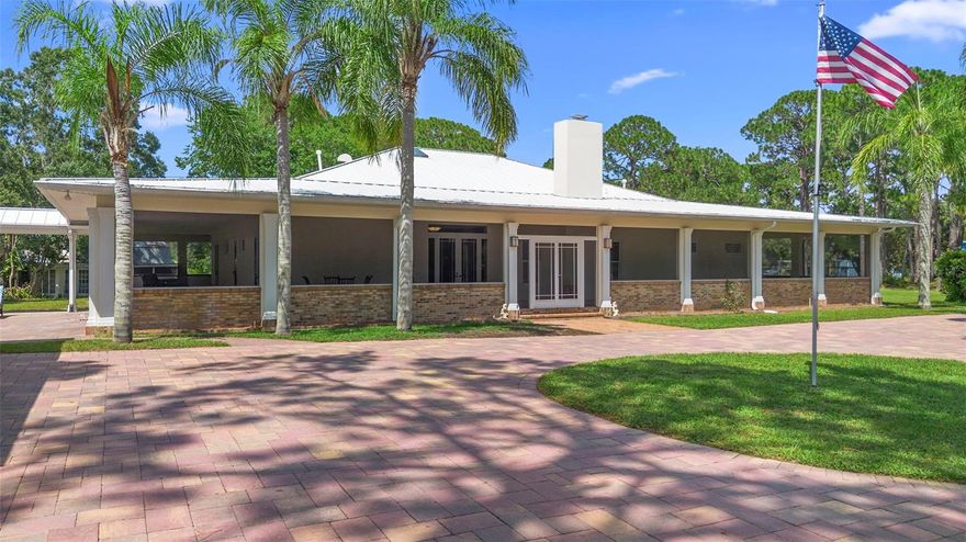 Step into timeless elegance where a custom-designed, fully screened 4,000-square-foot wrap-around porch takes center stage. Encompassing every angle of the home, this extraordinary space blurs the line between indoor comfort and outdoor tranquility. With nine sets of French doors leading to the porch, you’ll enjoy seamless access to fresh air, peaceful views, and over 7,000 square feet of combined living space. Set on 2.66 acres of meticulously maintained and fully fenced grounds, this property offers both beauty and function in a private, park-like setting. As you arrive, a hand-laid brick paver driveway bordered by manicured hedges welcomes you to a grand roundabout, its centerpiece a stately flagpole- an introduction that sets the tone for the elegance within. Inside, soaring 12-foot ceilings, detailed crown molding, and real oak hardwood floors create an atmosphere of sophistication. The expansive family room, anchored by a stately wood-burning fireplace, invites relaxation and entertaining alike, while the chef’s kitchen- with granite countertops, a gas range, prep sink, and gathering space, makes every meal a special occasion. A secondary family room with custom built-ins provides the perfect media space or display area, while each bedroom serves as a private retreat with en-suite bathrooms and direct porch access. The primary suite is a sanctuary, complete with a connected office or library, spa-inspired bathroom featuring a freestanding tub and dual vanities, and a generous walk-in closet. From nearly every room, views of mature pines and a tranquil pond enhance the feeling of seclusion. Outdoors, a brick-lined courtyard connects to the oversized two-car garage via breezeway, while a secondary gated entrance offers convenience for trailers, large deliveries, or additional parking. With ample space for cross-fencing and a large outbuilding, the property is steps away from an equestrian’s dream. The property has been meticulously maintained and updated, including a whole house Generac Generator installed, updated HVAC system 2024, 2 Hot Water Heaters both replaced 2024, interior and exterior paint, installed gutter guard system, and much more. Offering unmatched character, functionality, and a rare harmony with nature, this estate is more than just a home- it’s a lifestyle.