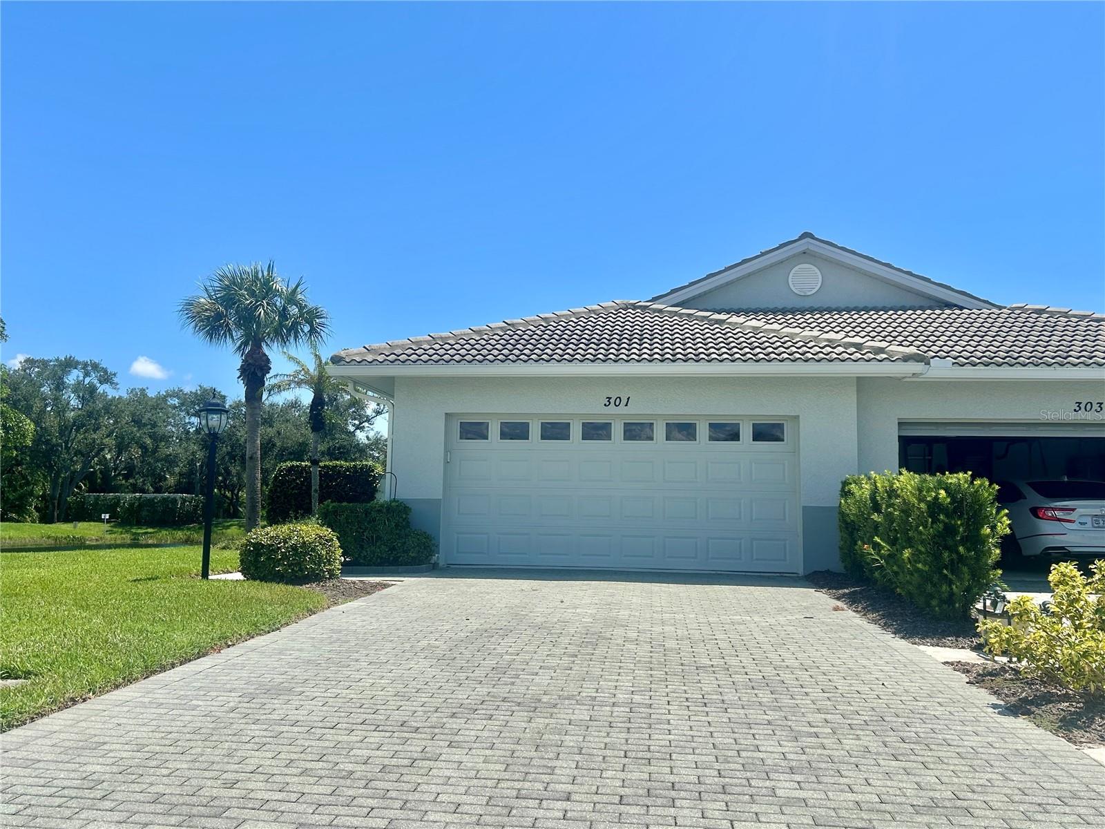 Auburn Hammocks, a private gated enclave of just 47 homes with a community pool and clubhouse, is the perfect setting for this immaculate, maintenance-free end-unit villa. Situated on a private lot with serene lake views, this home welcomes you through a gated courtyard—an ideal spot for relaxing or entertaining outdoors while relaxing watching the lake wildlife. Inside, the open split floor plan offers a seamless flow with high ceilings, abundant natural light, and an eat-in kitchen designed for everyday living. The two bedrooms are spacious and private, while the den with custom built-in Murphy beds provides flexible space for guests or a home office. Notable features include impact-resistant windows, a water treatment system, pavered drive, inside laundry room, and a 2-car garage. Just minutes from Historic Downtown Venice, Gulf beaches, shopping, dining, and I-75, this villa combines comfort, style, and convenience. Don’t miss this opportunity to enjoy the best of Florida living!