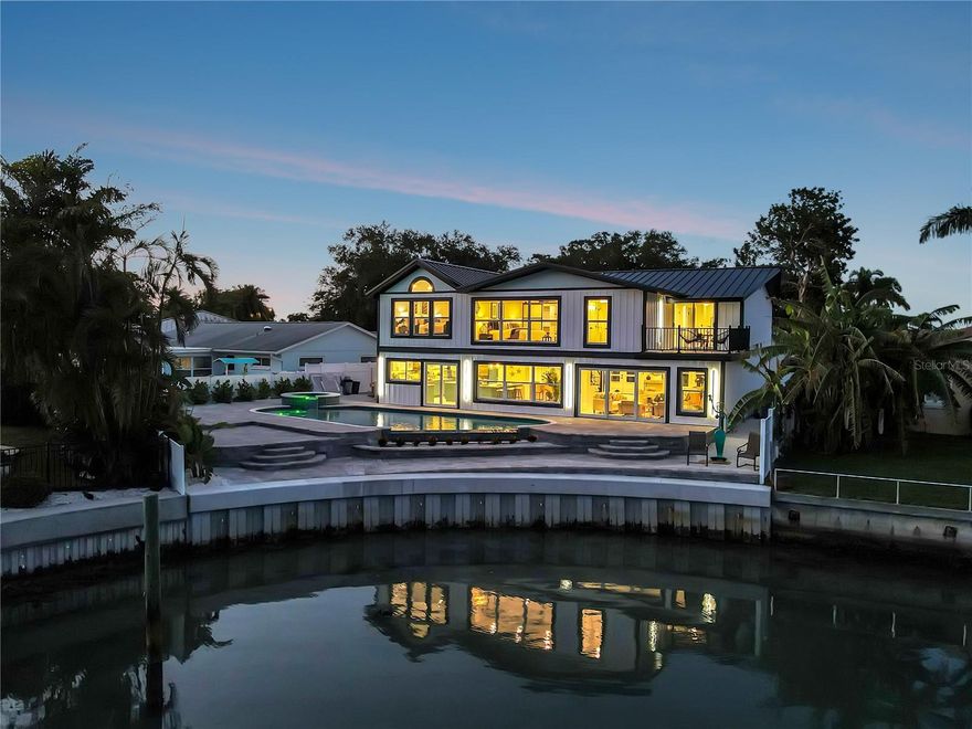 Cutting edge coastal contemporary elegance describes this fully renovated 5 bedroom, 5 bathroom, 4250+ SF waterfront home in the highly sought after Yacht Club Estates neighborhood in St. Petersburg. As you walk up the paver walkway, you will enjoy water views before you walk through the front door. As you enter thru the double doors, your view becomes water and a custom, built-in glass wine pantry. To your left there are three different sitting spaces for entertaining guests and family events. Walking past the wine pantry, on your right, you are greeted with a built-in, custom Bianca-Cielo quartz waterfall dining room table that seats 10. It is complemented by a Schonbek Beyond crystal chandelier. Just beyond you will find the professional chef’s kitchen that Coastal Living would be jealous of. Top of the line appliances including a 48” Sub Zero refrigerator, 48” Thermador Pro Grand dual fuel range, convection warming drawer, ice maker, wine and beverage fridge to name a few. Enjoy the custom glass double door entry to one of your three pantries. From the kitchen you are in the crow’s nest looking at breathtaking water views and the brand new heated, salt water pool with elevated spa, waterfall infinity edge, beach entry, sun shelf, LED bubblers and several levels of deck space for entertaining. Walk out your 12 ft folding sliders from the great room area or choose the 6 ft sliders by the kitchen as both go out to your extensive, tiered pool deck. To your right, is your brand new outdoor kitchen. Upstairs you will find your five bedrooms, which includes two true master bedrooms both with breathtaking water views. As you walk from the first to the second master bedroom, you have a double door entry welcoming you to your large sleeping and sitting area with designer minibar and vaulted ceilings. To the right is a luxurious master bathroom and a closet with a special surprise awaiting the lady of the house. On the other side of the second floor there is an ensuite bedroom that functions great as an office with beautiful water views and its own tiled balcony deck. A few other notable features of this Yacht Club Estates masterpiece include a new 2023 standing seam metal roof, a 2023, 9-ton dual zone HVAC system with all new duct work, a 120 gallon commercial water heater, all new hurricane impact windows and doors, a new 2022 vinyl seawall and cap, a handcrafted billfish mailbox and mermaid backyard shower and new, tropical landscaping with irrigation. This house has been structurally re-engineered for safe, comfortable living and allows seamless indoor-outdoor living without going up or down stairs or an elevator. This showcase home has so much to offer and tons of curb appeal from every angle. This gem is sure to go quick!