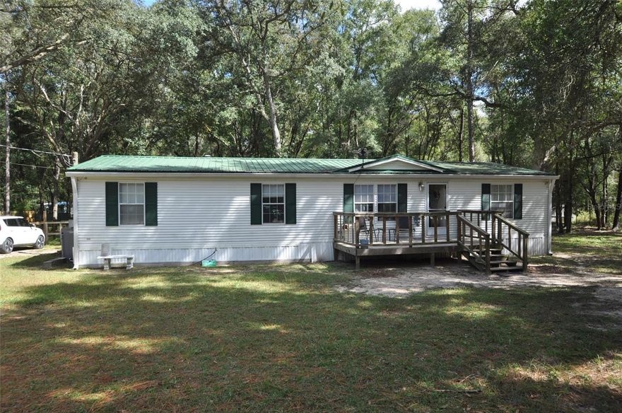 COUNTRY OASIS ON 1.33 ACRES IN ARCHER. Escape to your own country oasis in Archer, Levy County! Nestled on a sprawling 1.33 acre lot, this impeccably maintained Triple-Wide Manufactured home offers a perfect blend of comfort and tranquility. With 3 bedrooms and 2 baths, it's an ideal family haven or a peaceful retreat. The heart of this home is its spacious kitchen with a delightful breakfast/dining area, a hub for family gatherings. Vaulted ceilings and gleaming laminate flooring create an inviting ambiance. Cozy up by the living room's fireplace on cool evenings, or step through the sliding glass doors onto the back deck for fresh air and serene views. Morning coffee on the large front deck, surrounded by nature, is a daily pleasure. The property boasts partial fencing, including 6-foot privacy fencing on two sides, ensuring your peace and seclusion. A durable metal roof and a convenient storage shed add practicality to this charming retreat. Discover the rural charm of Archer, Florida, with this wonderful property. Whether you seek a permanent residence or a weekend escape, this oasis offers endless possibilities. Don't miss this unique opportunity to make it your own!