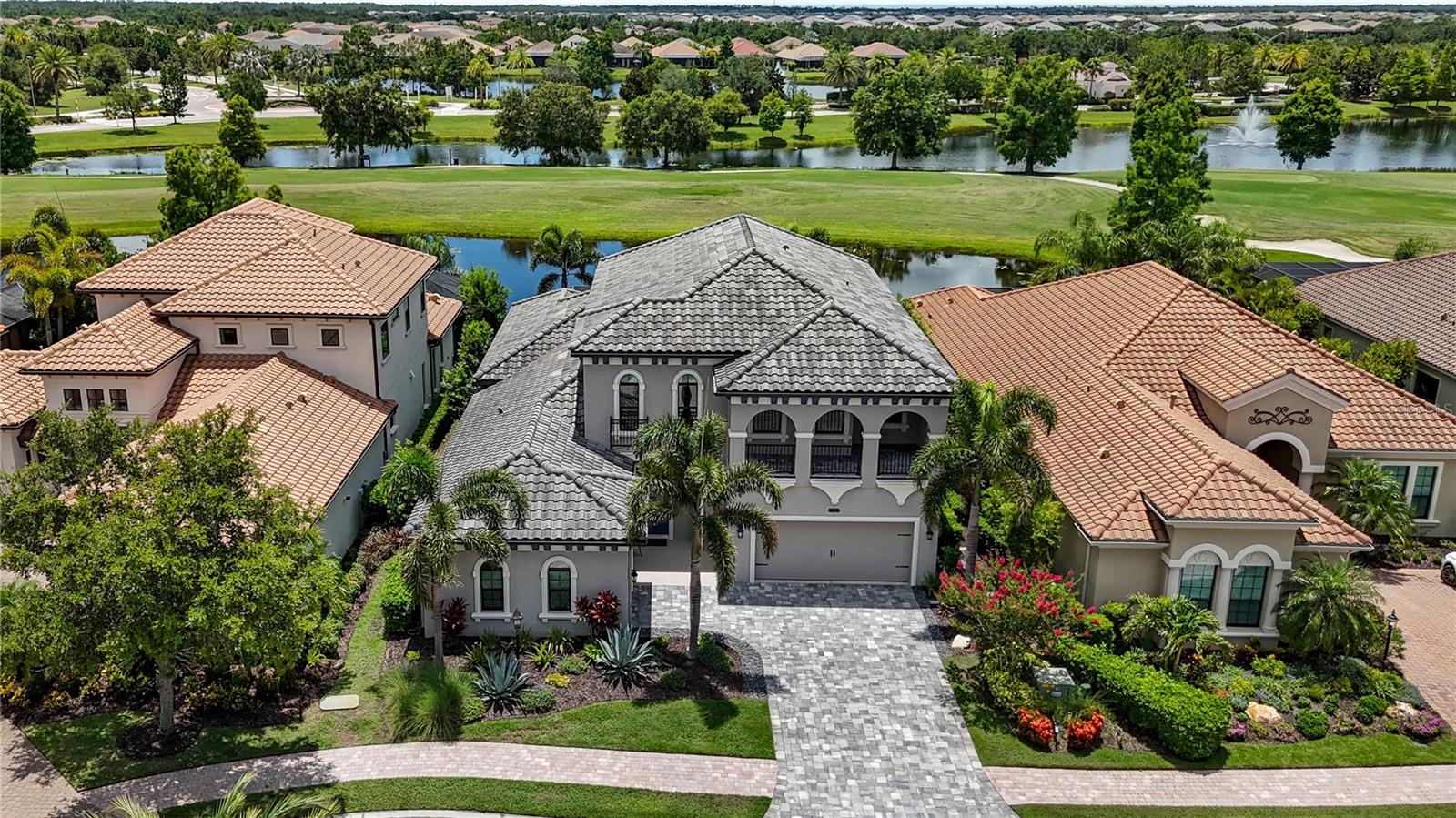 Modern luxury and sophisticated design come together in this Palazzo-model Cardel pool home, ideally located behind the gates of the highly sought-after Country Club East at Lakewood Ranch. Nestled on a quiet cul-de-sac lot with panoramic lake and golf-course views, this two-story Italian Villa offers 3,883 sq ft of meticulously designed living space, including five bedrooms, 3.5 bathrooms, a dedicated office, an upstairs bonus room, and a spacious three-car garage. Enjoy unparalleled convenience—stroll to the Country Club and neighborhood amenities, or hop on your bike or golf cart to top-rated schools.
Step through the grand entry into an airy open layout flooded with natural light, accentuated by soaring 20-foot ceilings and expansive picture windows framing serene water and fairway vistas well back from the cart path. The gourmet kitchen dazzles with custom white cabinetry, extra-thick quartz countertops, high-end Wolf stainless-steel appliances, and an expansive butler’s pantry—perfect for tucking away small appliances and keeping workspaces pristine. Custom lighting, fans and built-out closets elevate the living space. Abundant storage is thoughtfully integrated throughout.
Discover one of the very few true five-bedroom homes available in Country Club East—an increasingly rare opportunity in this coveted enclave—plus a dedicated office. The main-level primary suite is a private haven, boasting rich hardwood floors, dual walk-in closets, and a spa-inspired bath with dual vanities, and a frameless glass shower. A versatile guest suite and formal dining or home-office complete the first floor. Upstairs, an oversized bonus room—ideal for a home theater or fitness studio—is accompanied by three additional bedrooms with walk-in closets, a full bath and a wet-bar balcony landing.
Outdoor living is effortless, with a generous covered lanai, fully equipped outdoor kitchen, and a convenient pool bath with extra storage—all overlooking a heated salt-water pool and spa within a full-screen enclosure.
Windy Hill is an active enclave celebrated for its strong sense of community and festive spirit—a true holiday hotspot—while Country Club East amenities, including The Retreat’s resort-style pool and fitness center and The Lodge’s dining and social events, are just a short walk or golf-cart ride away. Minutes from Lakewood Ranch Main Street, Waterside Place, Sarasota’s award-winning beaches, and cultural venues, this light-filled masterpiece embodies the ultimate Florida lifestyle. Your perfect retreat awaits.