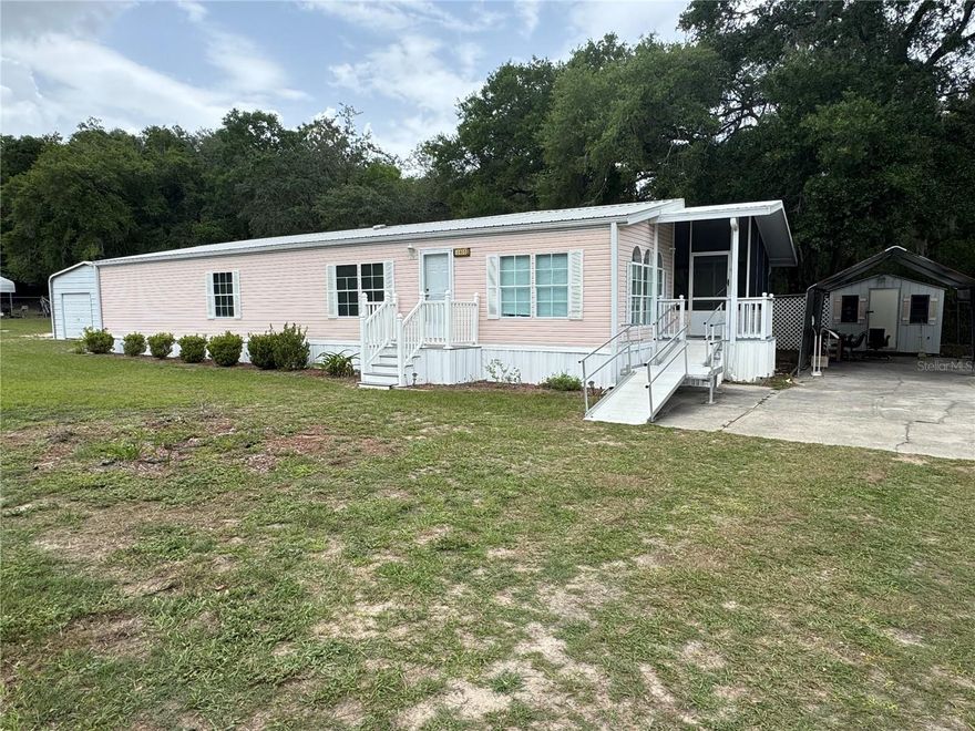 A fiddler's dream? Please come explore this 3/2 with a metal roof, double-wide with gutters, completely fenced in with two sets of gates that sits on .46 acres. Take advantage of the covered, screened-in Florida room with a ramp, an oversized yard with a large detached workshop, 2 sheds, ample concrete parking, covered parking, and a rear deck. Now let's explore the interior of this residence. Each room offers generous space, dual sinks in the primary bedroom, an inside utility room with a folding table, a kitchen nook, and more. Contact us today to schedule your private tour.