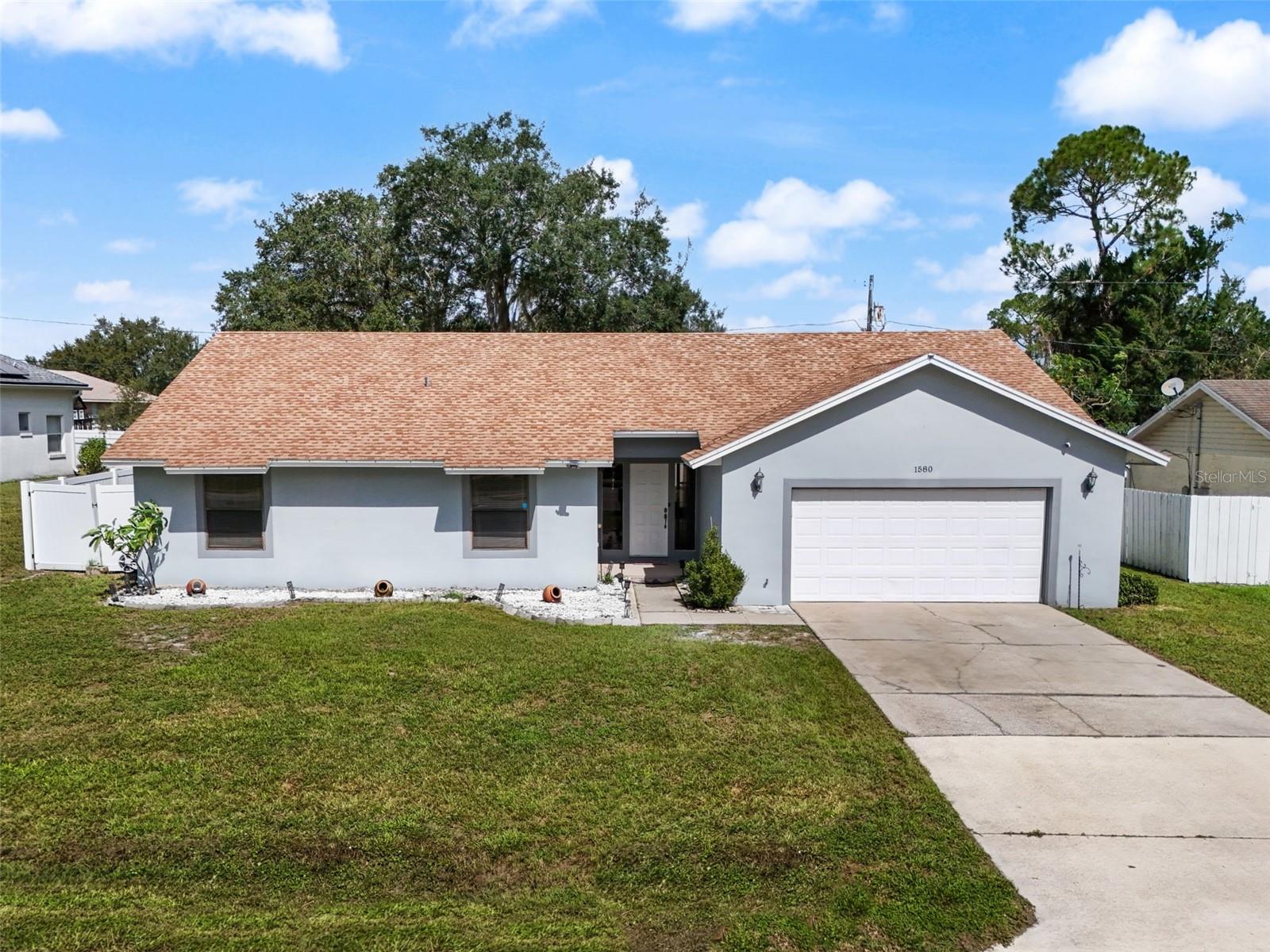 One or more photo(s) has been virtually staged. Welcome to 1580 E Normandy Blvd!!
This lightly lived-in, completely move-in-ready home is ready for its next owner! Offering true peace of mind, the roof was replaced in December 2020, the garage door was updated the same year, and the water heater was installed in 2017. Fresh interior and exterior paint give the home a clean, modern look, while the thoughtful updates and meticulous care throughout make it feel brand-new.
Step inside and you’re immediately greeted by soaring vaulted ceilings that create an open, airy feel throughout the main living area. The spacious family room centers around a beautiful brick-front wood-burning fireplace, adding timeless warmth and character to the space. Large sliding glass doors fill the room with natural light and open to the screened porch, seamlessly blending indoor and outdoor living. Luxury vinyl plank flooring enhances the main living area, stylish, durable, and easy to maintain.
The large, open kitchen is the perfect heart of the home, offering plenty of counter space, a spacious dining area, and stainless-steel appliances including a refrigerator, range, and microwave. Whether you’re hosting a family gathering or a quiet dinner for two, the open layout keeps everyone connected.
The primary suite provides a true retreat with generous proportions, ample natural light, and direct access to the backyard. There’s plenty of closet space, a dressing area with dual sinks, and room to create a cozy sitting or work nook. Three additional bedrooms give you the flexibility for guests, a home office, or hobbies- each comfortably sized and bright.
Step outside to enjoy the best of the Florida lifestyle. A screened-in back porch overlooks the fully fenced backyard, offering privacy, shade, and room to play. The yard is dotted with mature oak trees and features a beautiful pergola on a concrete slab- ideal for outdoor dining, barbecues, or simply relaxing under the stars. The lot’s size provides ample space for a garden, play area, or even a future pool.
Located in an established Deltona neighborhood with no HOA, this property offers freedom and space while remaining close to everyday conveniences. Conveniently situated near I-4, you’ll enjoy an easy commute into Orlando for work or entertainment and a quick drive up to Daytona Beach or New Smyrna for a day by the water.
Lightly lived in and never rented, this home has been lovingly maintained as a seasonal residence and shows true pride of ownership. With its open floor plan, vaulted ceilings, fireplace charm, and outdoor living potential, 1580 E Normandy Blvd delivers comfort, functionality, and value all in one package.
Homes this clean and move-in ready on private, fenced lots rarely come available, schedule your private showing today and make this one yours!