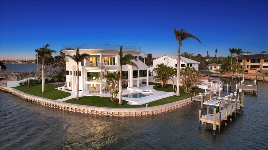 Three levels of modern updates define this remarkable bayfront retreat in one of Sarasota’s most sought-after locations. This home is perfectly positioned on an oversized corner lot with nearly 250 feet of frontage on two sides, offering unparalleled views and seamless access to Sarasota Bay. A newly installed dock and kayak launch make this a true boater’s paradise. A gated entry and winding pavered driveway set the stage for the architectural beauty that awaits inside. The nearly 5,400-square-foot interior has been masterfully reimagined, with sleek designer finishes, custom built-ins, and an open-concept layout that maximizes the breathtaking bayfront backdrop. Expansive walls of glass invite an abundance of natural light, while oversized porcelain tile flooring connects each space with contemporary sophistication. The main living area is an entertainer’s dream, with a spacious great room anchored by a built-in wet bar, and a formal dining area that capitalizes on the home’s panoramic views. The chef-inspired kitchen is a showpiece of style and function, featuring custom cabinetry, floating open shelves, quartz countertops, mirrored tile backsplash, an oversized island with seating, and top-of-the-line stainless steel appliances—including a built-in coffee bar. A French door leads to the waterfront terrace, where dazzling sunset views create the perfect evening ambiance. A private sanctuary awaits on the top level, where the primary suite offers a luxurious escape with its own waterfront terrace and spiral staircase leading to the outdoor living areas below. The walk-in closet is a curated masterpiece of custom built-ins, while the spa-like en-suite bathroom showcases exquisite details, including gold fixtures, floor-to-ceiling designer tile, soaking tub, and glass-enclosed shower with multiple showerheads. The ground level is designed for comfort and versatility, with two additional guest suites that open to the pool deck. The largest of these suites features an en-suite bathroom and built-in dry bar. Outdoor living is equally exceptional, with a resurfaced heated swimming pool and spa, expansive deck, and covered cabana areas that create an inviting retreat for waterfront relaxation. The premier location of this exclusive residence is minutes from downtown Sarasota’s vibrant arts and dining scene, St. Armands Circle’s luxury shopping, and the world-famous beaches of Siesta Key and Lido Key.