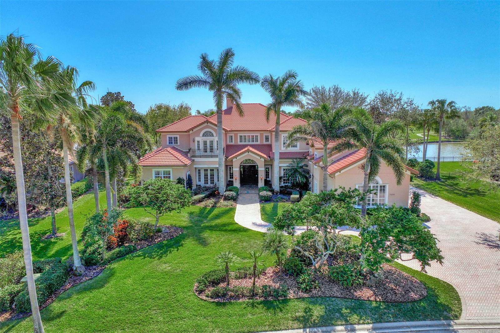 This Beautifully crafted, one of a kind, custom John Cannon home is situated in the upscale gated community of Lakewood Ranch Country Club Village on Florida's beautiful gulf coast. This property boasts TWO Master bedroom suites, one on the upper level and one on the ground floor, five bathrooms, a guest bedroom, a hobby Room, media room, wet bar, and an office. In addition, it backs up to the Lake and Golf course for an exquisite view to call home. As soon as you pull up to the front home, you will notice a beautifully landscaped front yard, and 3 over sized car garages. When you enter through the double Mahogany front doors, you will be greeted with 12 Grand Columns, a high rise ceiling, a magnificent seating area featuring a floor to ceiling coral fireplace, and the view of the lake and golf course. Through the 9 French doors to the screened in lanai, you can take a dip in the over sized pool and jacuzzi that is complimented by an outdoor grill, sink and an outdoor shower. As you enter back into the home, you will see a large kitchen oasis complete with marble counter tops, microwave/ oven combo, built in desk with full cabinetry, walk in pantry, a triple sink and a large center island with a salad prep sink. The Kitchen is complimented by the spacious family room with the lake and golf course views in the back of the home. One of the master suites that is located on the first floor has direct access to the pool/ lanai area, large full bath, seating area and 2 large his and her closets. The elevator or stairs can take you to the upper level of the home to the second master suite with balcony and seating area, guest bedroom with full bath, office, and media room. You will take notice of the crown molding in all of the living areas and tray ceilings in the master suites. Windows are double paned with plantation shutters installed in the windows facing the front of the home and custom drapery in the back of the home. This home is just a short drive to an International Airport, museums, theaters, downtown Lakewood Ranch and all that Bradenton and Sarasota has to offer, not to mention this home is just 3 blocks over from the clubhouse! Lakewood Ranch Country Club membership is purchased separately. You don't want to miss this rare opportunity!