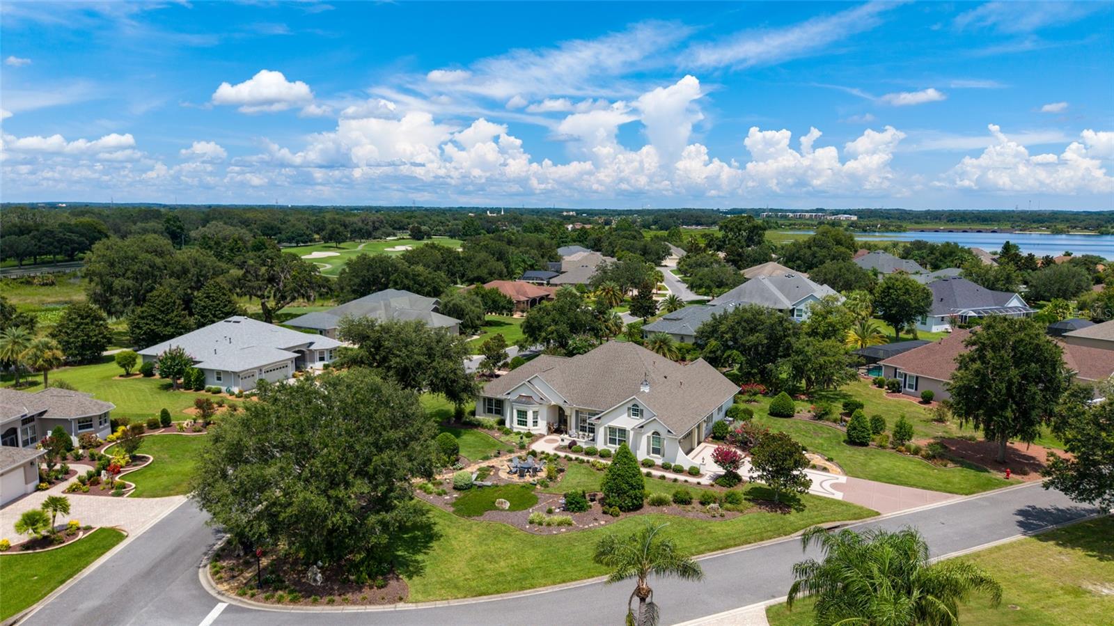 The first time offered for sale since new, this Sanibel premier model home with 3 bedrooms, 2 baths and a private pool is located in the extremely convenient location of Bridgeport at Lake Sumter, just north of the town of Lake Sumter Landing. The Sanibel model is architecturally pleasing with its multiple rooflines, large windows, tall ceilings and side load garages. As soon as you drive up to this particular Sanibel model home, you will be impressed by the house’s commanding presence on this over half acre corner lot, and the spectacular landscaping that features walkways, seating areas, and numerous varieties of mature bushes and flowers. Stepping inside, note the spaciousness and warmth of this home with its tall ceilings and light-filled rooms. Notice the two separate gathering areas, living room and family room, perfect for entertaining. There are custom built lighted bookcases with storage in the family room, and a sizable kitchen with granite counters, a large center island, and pantry closet with roll-out shelves. For casual dining there is barstool seating at the counter and a separate kitchen eating area. For larger dinner parties, a generous size dining room is adjacent to the kitchen. Continuing through the home, the primary bedroom is gracious and relaxing with plenty of extra space and it features built in wooden storage cabinets and engineered wood flooring. The primary bath has both a Roman shower and a bathtub, double sinks and granite counters. An oversized walk-in closet completes the primary suite. Two guest bedrooms, each with luxury vinyl flooring, and a guest bathroom are positioned on the opposite side of the home for privacy. A separate laundry room is conveniently located near both the kitchen and the garage. An unusual feature of this oversized 2 car plus golf cart side-load garage is that it is air-conditioned by a separate mini-split unit. What a great way to maximize use of the garage in the hot summer weather. Going outside, the private pool is solar or gas heated and situated in a large, screened area with ample seating and room for sunbathing. The extensive and well-placed shrubbery ensures privacy for all enjoying the pool area. This large property has been lovingly landscaped with walkways, numerous seating areas, and a firepit area, all with a striking selection of shrubs, trees and flowers. New roof-2020, new gas water heater-2023, new HVAC-2020. One year Broward home warranty included. Please stop by soon to decide if you could be the proud new owner of this impressive Villages home!