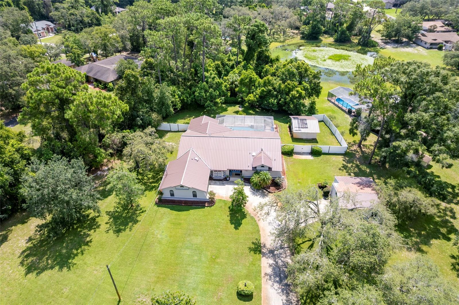 Welcome to your private Florida paradise! This custom-built 4-bedroom, 2-bath, 2-car garage home is hitting the market for the first time, cherished by its original owners. Nestled on just under 1 acre (.9653 acres), the fully fenced rear yard boasts two outbuildings. The first, conveniently located off the main drive, offers ample space for an extra car, boat, or golf cart, featuring a great workshop. In the expansive rear yard stands another impressive outbuilding, perfect for storing lawn and pool equipment or converting into additional living or lounging space.
Upon entering through the double doors, solid wood floors grace the foyer and formal dining areas, while the impressive living room dazzles with vaulted ceilings and sliding doors opening to the sparkling custom saltwater pool. To the right, the primary suite delights with spacious closets and an ensuite featuring split solid wood vanities with granite countertops, separated by a convenient pocket door. A skylight enhances the natural light in the bathroom, which includes a separate tub and walk-in shower.
The home's three additional bedrooms are generously sized, two offering walk-in closets. The guest bathroom has been tastefully updated with granite countertops and a rich solid wood vanity. Two additional glass door access points lead to the pool, patio, and backyard oasis.
This home boasts a custom pool, 9 feet deep at its deepest point and equipped with a diving board and playful water-spraying dolphins for endless entertainment. Recently upgraded with a new 2025 A/C system and metal roof, the property ensures modern comfort and durability.
What the current owners cherish most about this home is its serene atmosphere, free from HOA restrictions and with no rear neighbors, allowing them to enjoy peaceful swims and morning coffee with the sunrise. Located conveniently near Highway 54, Trinity, Tampa International Airport, and Florida's renowned beaches, this property offers both tranquility and accessibility.
Don't miss out—call today and make this Florida country retreat, complete with a 1-year home warranty, yours tomorrow!