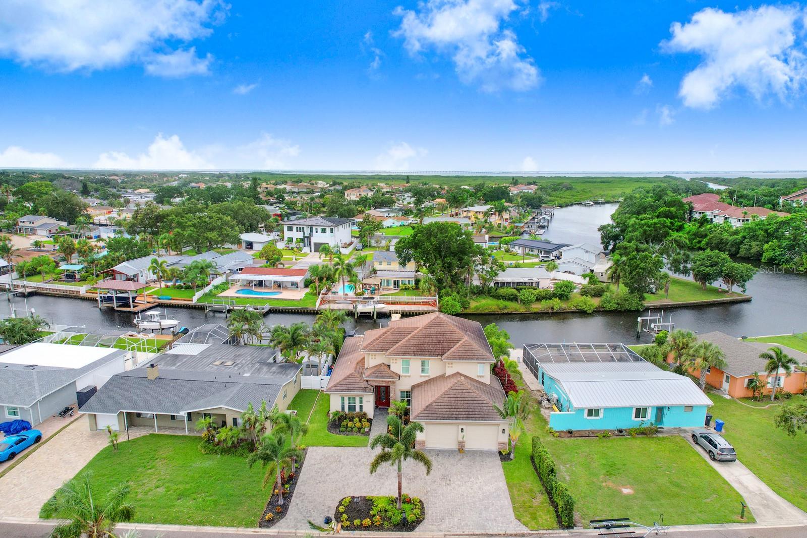 Presenting a boater’s paradise... literally minutes to the open Bay! Spectacular luxurious living! Two-story home perfectly combines luxury, style and functionality. Quality custom built in 2016, beautifully updated and offering nearly 3,300 sq ft of extravagant living. Canal front, lushly landscaped, grand pool home with 4 bedrooms, 4.5 baths and an oversized 2 car garage elevated with an extended brick-paver circular driveway and stone-wrapped front accents. Endless upgrades include solid designer interior doors, upgraded base & custom trim, plantation shutters, custom closet systems in each bedroom & all-important impact windows. Leaded glass entry brings you to soaring ceilings with transom windows providing natural light onto breath taking designer porcelain tile. Living spaces are open and exquisite with formal dining room upon entry, huge Great Room with designer porcelain tile, a striking accent wall and centered by a built-in electric fireplace. The kitchen is a splendid chef’s kiss… custom cherry cabinetry with 42” uppers, 2 lazy Suzanne’s, pull out butler drawers, raised breakfast bar with designer pendant lighting, granite counters with dual under mount SS sinks, tile backsplash, dry bar and wine rack, large working island, SS appliances including 3 door refrigerator, café style ceran top range, built in microwave and dishwasher along with full wall pantry with custom shelving. Huge laundry room with upper & lower cabinetry, folding area and SS utility sink. The spacious primary sanctuary is conveniently located on the main floor. The suite boasts plank tile flooring, coffered ceilings, sliding glass doors to the lanai, posh ensuite with dual vanities, tower cabinetry, free standing soaker tub, full walk-in frameless shower with designer tile, water closet and 2 amazing, custom walk-in closets. This inviting retreat area also offers a second bath fashioned as a powder room, half bath, boasting a striking designer vanity. An additional bedroom is located at the front of the main floor featuring a walk-in closet and its own ensuite bath with walk-in shower. The striking wood staircase is accented by wrought iron and leads to the spacious 2nd floor loft overlooking the great room and offering endless possibilities. The two additional bedrooms are spacious and have full wall closets. Convenient hallway bath features dual vanities, tower cabinetry, separate water closet, and tub/shower combination. Extend your living and entertaining space to your outdoor waterfront paradise! Pool side kitchen, covered lanai with remote controlled retractable screens, brick-paver pool deck (reset 2025), show stopping, heated pebble tec pool with raised spill over spa and surrounded by lovely vinyl fencing. The homes 4th full bath is true cabana style with a pedestal sink and walk-in shower. Beyond the pool sanctuary is boating nirvana! A brick paver walk leads to a trek deck boat dock that includes a jet ski lift and 10K capacity boat lift (motor replaced 2025). The home is perfectly situated just two houses from Channel A and only a brief 5 minute boat ride to the Bay!!! Notable recent updates include first floor interior & loft painted (2024), new variable speed pool pump (2025). This is an absolute must see! A rare find offering the epitome of luxurious coastal living! Bonus-the Tampa Shores community offers a boat ramp for homeowners! Make your waterfront dream a reality! Schedule a showing today!