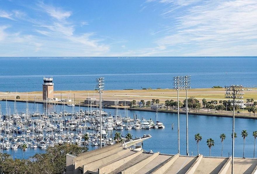 This one-of-a-kind penthouse at The McNulty Lofts is designed to captivate from the moment you step inside. Inundated in natural light, the spacious layout is brought to life by floor-to-ceiling windows that span the entire east side of the condo, offering stunning views of Tampa Bay. This extraordinary residence effortlessly blends modern luxury with breathtaking scenery, creating a truly unparalleled living experience. The breathtaking views are perfectly matched by the exquisite designer-grade finishes throughout this stunning penthouse. The light and airy kitchen has been thoughtfully updated with luxurious marble countertops that flow seamlessly into the backsplash and center island, creating a cohesive and elegant design. The all-white custom cabinetry, complete with soft-close drawers and pull-out racks, offers both style and functionality, while a built-in nook provides the perfect space for a coffee bar and wine fridge. Completing the space are all-new Bespoke appliances, including a state-of-the-art stove, oven, dishwasher, refrigerator, and microwave, ensuring a modern and sophisticated culinary experience. The open concept living spaces serve as the vibrant heart of this stunning penthouse, offering an organic flow that perfectly complements the true split floor plan. The unique layout includes a spacious sitting area off the primary suite, designed to double as the ultimate workspace. Immersed in natural light, this room redefines the home office experience. Say goodbye to uninspiring, tucked-away workspaces, making this one of the most enviable home offices in downtown St. Pete. This stunning office space doesn’t sacrifice functionality for beauty. Custom-built bookshelves and storage line the back wall, providing ample space for organization while enhancing the room’s sophisticated design. The sitting room seamlessly transitions into the expansive primary bedroom, where the floor-to-ceiling windows continue to impress. Imagine waking up each morning to breathtaking, panoramic views of the sun rising over Tampa Bay—a daily masterpiece to start your day. Or sleep in with automated Lutron black out window treatments in your primary. The luxury of this penthouse extends into the primary walk-in closet. This generously sized closet boasts custom-built features, offering two thoughtfully separated sections and an entire back wall of sleek shelving—perfectly suited to showcase your collection of bags and shoes with style and ease. The second bedroom rivals the primary in size and features a versatile layout with an ensuite bathroom. An oversized walk-in closet with custom-built shelving provides ample storage, while soaring 11-foot ceilings create space for a loft above the closet and laundry room—ideal for seasonal items. Additional upgrades include Lutron window treatments, designer lighting, and a high-performance Trane HVAC system (2022). McNulty Lofts offers a boutique living experience with only 83 residences, on-site management, a fitness center, and a newly renovated lobby. Residents enjoy two private parking spaces and a prime Downtown St. Pete location. Step outside to top-tier restaurants, shops, serene parks, museums, and iconic theaters like The Dali Museum and The Mahaffey Theater. With landmarks such as St. Pete Pier and Vinoy Park nearby, this penthouse blends luxury, culture, and convenience for an extraordinary downtown lifestyle.