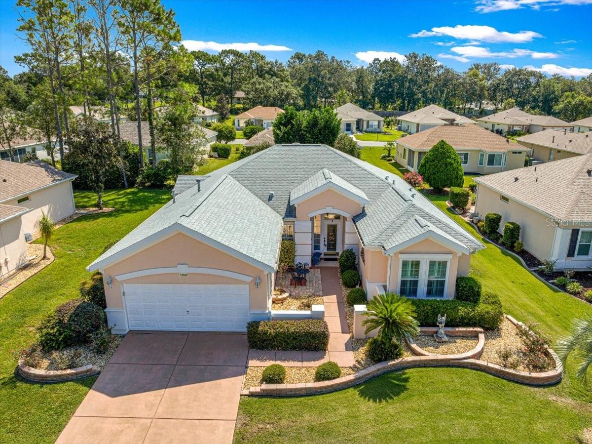 Discover this well-maintained 2 bedroom, 2 bath home plus a den in the highly sought after 55 plus premier golf community of Del Webb Spruce Creek Golf & Country Club. This stunning Madeira floor plan offers exceptional curb appeal with a stained driveway, stacked-stone landscape walls, and a welcome and inviting courtyard entry leading to an elegant leaded glass entry door. Step inside to find touches such as crown molding and plantation shutters, adding sophistication to every room. Tile flooring graces the foyer and all wet areas, while the separate den features parquet wood flooring, making it a perfect home office or flex space. The updated kitchen is a true showstopper, boasting white cabinetry, glass tile backsplash, Corian countertops, newer stainless-steel appliances, recessed lighting, and pendant lighting above the breakfast bar, while above-cabinet recipe windows allow for added light. Enjoy anytime dining in the breakfast nook with a charming bow window. The inside laundry and garage have added overhead storage. The spacious primary suite includes crown molding, plush carpet, a large walk-in closet, and a bow window for added space. The updated ensuite bath includes stone wainscoting, dual raised sinks, and a walk-in shower. The guest bedroom and bath are equally impressive, with crown molding and updates that include stone accents, a raised sink, and a therapeutic soaking tub. Additional highlights include extended garage for extra storage and housing the HVAC system, a tankless water heater for efficiency, and re-shingled roof in 2022. Designed for entertaining, the open floor plan flows seamlessly to the split Lania with one side having an expansive birdcage overlooking the well-landscaped backyard allowing for some privacy, while the other side is an enclosed lanai with a bonus second refrigerator and television. Furniture is available for purchase as a separate package. Enjoy resort-style living with golf, pools, fitness, dining, and endless activities in one of Florida’s premier active adult communities.