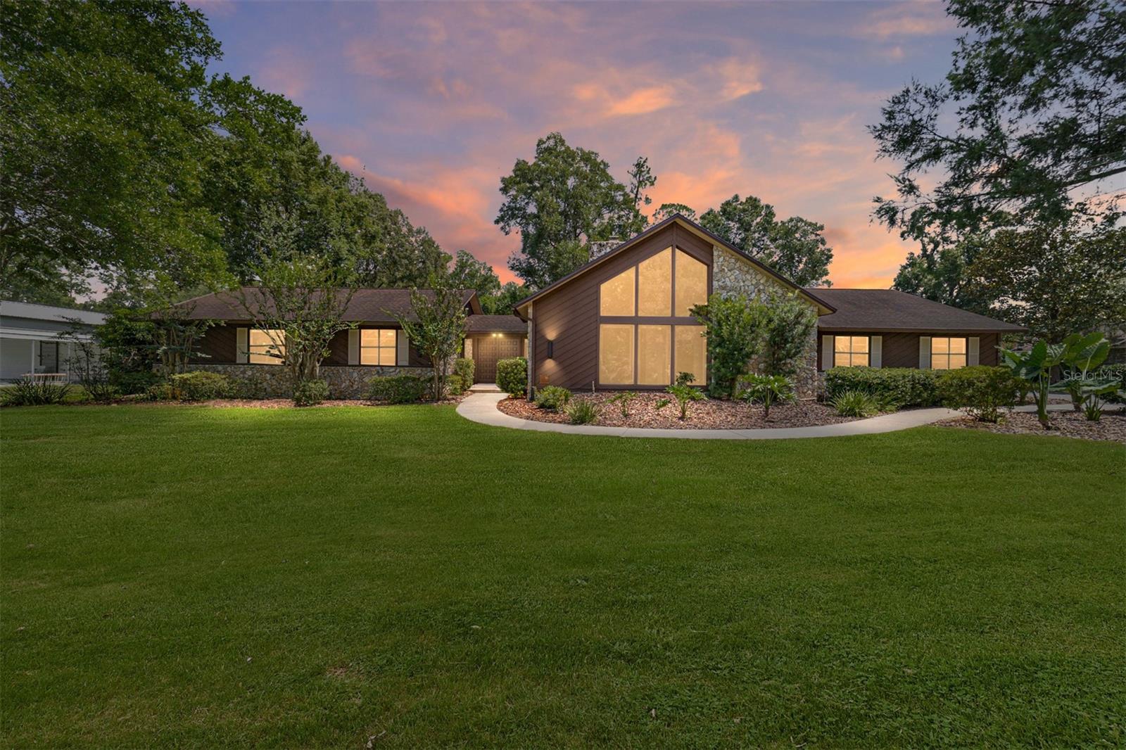 Rare Opportunity! Welcome to your Forever Home located in Oronoque; COUNTRY LIVING just outside city limits. Your CHATEAU getaway awaits you. Oronoque is predominantly occupied by Business owners. This 4 /2.5/ 3 (with Electric car charger) , provides 3296 living sq ft on .99 acre brings Rustic ambience, comfort and sophistication together. Perfect for family gatherings or formal entertaining. This Flexible FLOOR PLAN fits any household dynamic. Offering a living room, a formal dining room, breakfast nook, family room, which presents a spiral staircase leading to the upstairs Loft , which oversees the expansive outdoor entertaining oasis. Access your deck from several portals. From your inground pool, pool cage, pool deck & patio to your Brand NEW TREX Deck. You will spend your days enjoying your outdoor space, not maintaining it. TREX is your Composite, Never rotting, wood look & feel- lifelong deck.
As you enter, you are captivated by oversized hand carved doors. Opening into a foyer, which is the gateway to this retreat, embracing the country atmosphere views. Upon entering the expansive family room, you are greeted by a stunning 2 story stone Fireplace.. Stroll across to the kitchen where you can view both the front and rear yard. Care for family in your chefs kitchen with newer SS appliances, granite counters, closet pantry, and lots of real wood cabinets. Don't forget the built In desk area.
Wander over to the primary bedroom where your day begins with luscious views of trees, shrubs and flowering Camelias. Enjoy garden bath soaks before enjoying your private courtyard with towering butterfly & hummingbird plants. Luxury Amenities: motion sensor commodes, with automatic open & shut, complete with heated seat & bidet. The fun keeps going. This home boasts 3 more bedrooms on the other side with a Cabana bath, twin vanities. Pool towels are no problem with full size laundry room w/ built in folding station & added storage. Bedrooms Rooms complete with New Color changing lights & Ceiling fans, and more walk in closets. Bedrooms are nicely sized for larger furniture & beds. Your private escape to paradise but still within minutes to parks, shopping, dining, medical & entertainment. Enjoy the quieter side of Ocala without losing the convenience. ROOF 2021