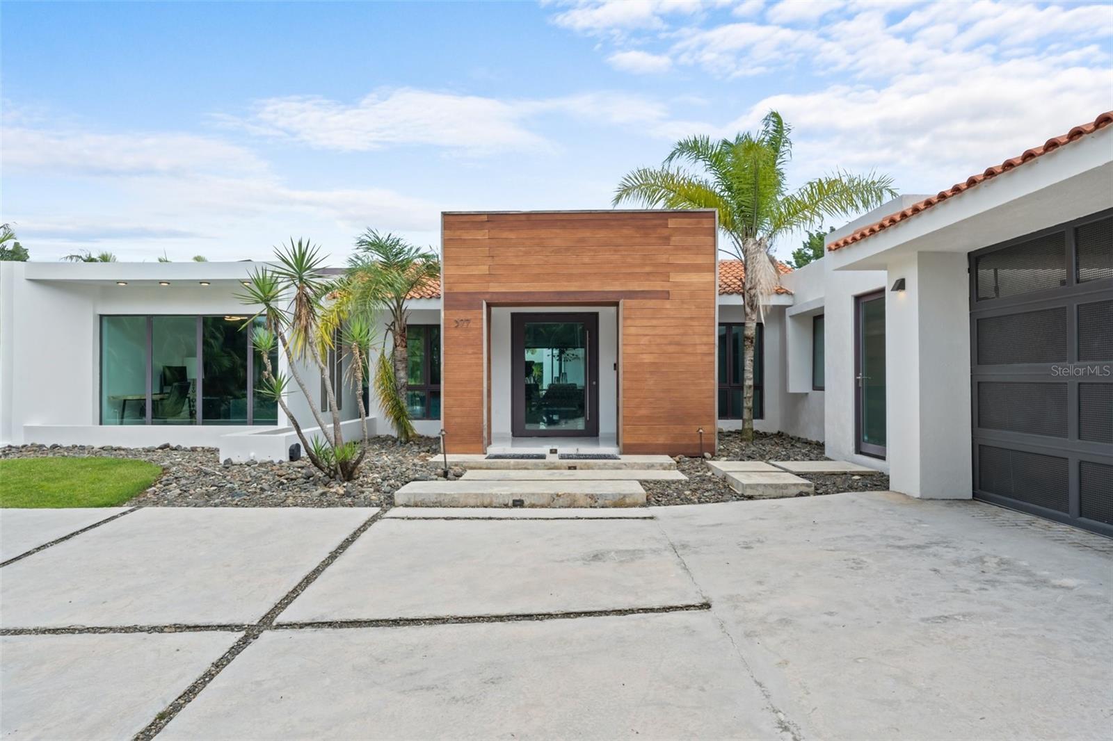 Located within the exclusive gated community of Dorado Beach East, this elegant single-level residence sits on a generous 1,921.49 sq. m. (0.47-acre lot), offering over 4,500 square feet of sleek, modern design and seamless indoor-outdoor living. With 4 bedrooms and 4.5 bathrooms, the home features a cool, refined palette, paired with custom lighting, high ceilings, and thoughtfully curated finishes throughout.
One of the bedrooms is designed with four built-in custom bunk beds and its own built-in closet, perfect for hosting family or guests. The open floor plan centers around a stylish kitchen outfitted with Wolf appliances, hidden cabinetry, a custom wine fridge, and clean-lined surfaces that flow into the spacious living and dining areas. Large sliding glass doors open to a pool terrace, creating a seamless connection to the outdoors.
The primary suite is a retreat of its own, with a tall-ceiling bathroom, blackout curtains, and a walk-in closet with built-in hampers. Every bedroom opens directly to the outdoor space, making the most of the lush surroundings and offering a constant connection to the outdoors.
Additional highlights include a mini powder bath, laundry room, and a detached 2-car garage. Outside, the pool, outdoor kitchenette, and grill island complete the ultimate setup for entertaining and enjoying Dorado’s coveted lifestyle. This property is a unique opportunity to own a stylish, modern home in one of Puerto Rico’s most prestigious resort communities.