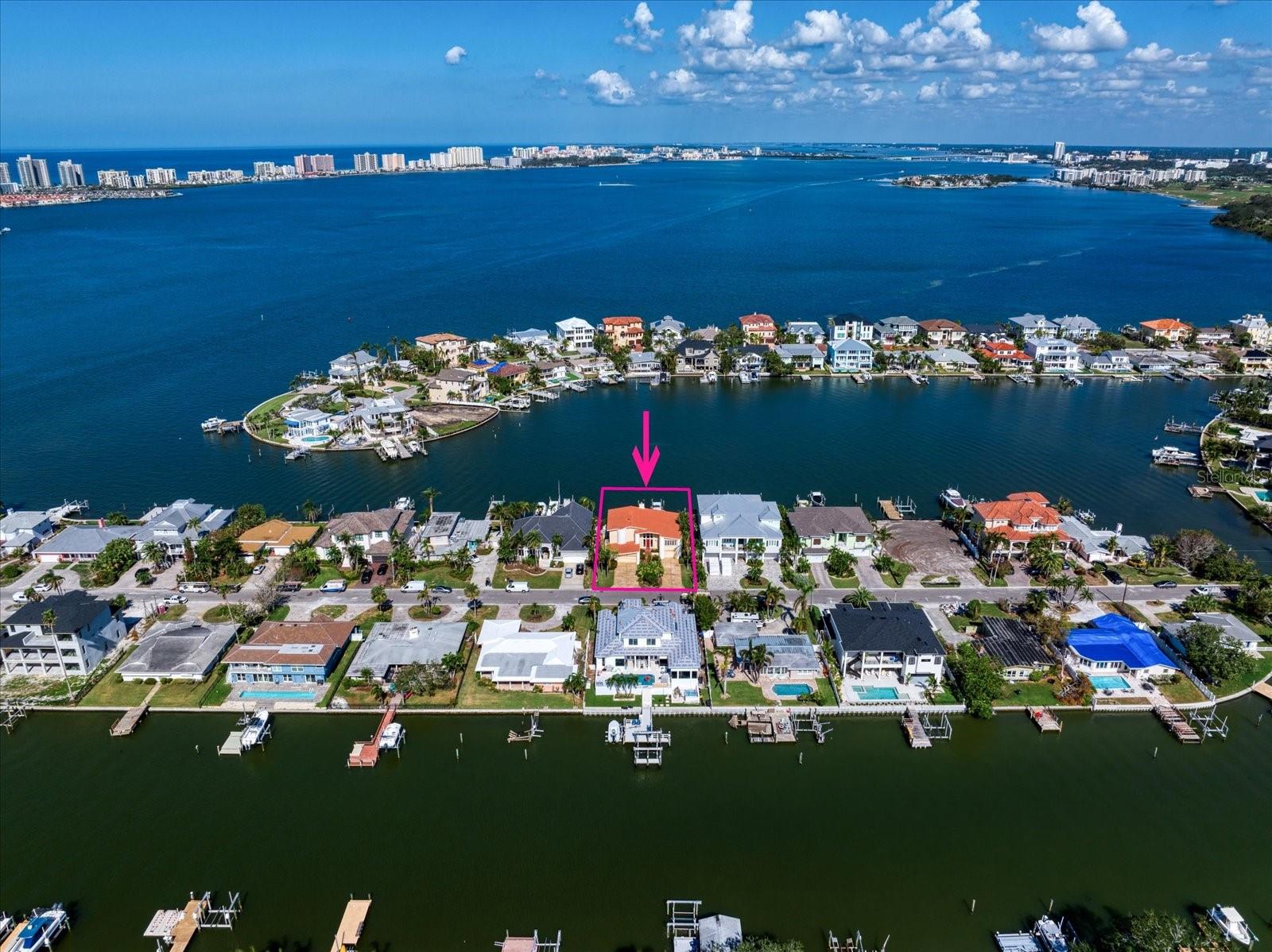 This stunning Belleair waterfront pool home is a perfect blend of modern elegance and coastal living, offering a lifestyle of luxury and tranquility. As you step through the grand entrance, 20-foot ceilings soar above, and natural light cascades across the gorgeous tile floors, highlighting the breathtaking water views that fill every corner of the home. The open floorplan revolves around a sleek, sophisticated white kitchen, featuring a 16-foot quartz island with seating and hidden pop-up outlets. Designed with entertaining in mind, this culinary space includes a built-in bar with a wine fridge, appliance garage, and a dedicated coffee hutch, creating a clean, clutter-free ambiance. Behind a barn door, a walk-in pantry offers ample storage, while a separate buffet bar with a chevron backsplash, floating shelves, and a sink is ideal for large gatherings. The kitchen flows effortlessly into a spacious family room and dining room, where French doors and ample windows provide an ever-changing backdrop of water views and a cozy fireplace sets the perfect mood for cooler evenings. Outside, a sparkling pool and expansive dock await—it's as if you’re floating on the water as you enjoy sweeping sunset views. For boating and fishing enthusiasts, the dock is equipped with a lift and a floating dock, making it easy to launch kayaks or paddleboards. Nature lovers will be captivated by the ospreys, egrets, and other shorebirds that call this area home. Retreat upstairs to the luxurious primary suite, a serene haven with two walk-in closets, a private balcony with a pergola, and mesmerizing water views. The ensuite bath has been impeccably updated with double vanities featuring light-up drawers and cabinets, quartz counters, a defogger mirror, a soaker tub, a private water closet, and two skylights. A catwalk overlooking the family room leads to two additional guest rooms, each well-appointed with plentiful closet space, natural light, and a shared hall bath. The ground floor boasts a spacious over-sized two-car garage on one side, while the other side includes a one-car garage with a workspace and full bath—ideal for storing water toys or working on hobbies. With a 9-foot elevation to the living floor, this home is equipped with storm shutters, sealed casement windows, French doors, and a raised pool with a waterfall feature for added peace of mind. Perfectly located near shopping, local dining, and two exclusive private golf clubs, this home is just a short drive from world-famous, white-sand beaches, making this the perfect home to make your Florida lifestyle dream become a reality.