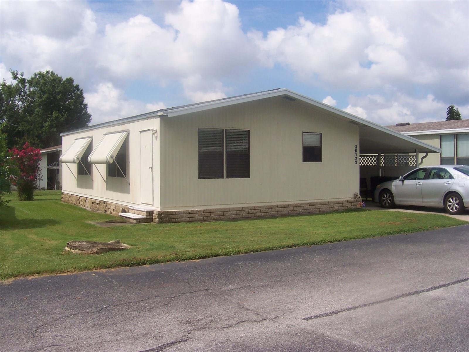 2 Bedroom and 2 baths, it's a must see and affordable!! YOU OWN THE LAND AND HOME! NO AGE RESTRICTIONS OR PET RESTRICTIONS!! AC UNIT AND HOT WATER TANK IS NEW WITHIN THE PAST YEAR! Nicely laid out kitchen with tons of cabinets and a pantry. Appliances included are range, refrigerator and dishwasher. Nice breakfast bar for meals on the go. Dining Room is conveniently located to kitchen and living room. Living Room is spacious and has four windows allowing for great natural light. Primary bedroom has its own ensuite bathroom with walk in shower. 2nd bedroom is spacious and located close to the guest bath which features a tub/shower combination. Nice quiet location in Sandalwood Mobile Home Community. Park features 2 swimming pools, basketball court and clubhouse. Home is located close to grocery stores, convenience stores as well as doctor's office and pharmacies. Short walk to bus stop if desired. Short drive to Wesley Chapel and Tampa plus easy access to I75 and I4. A great central location for any of your travels.