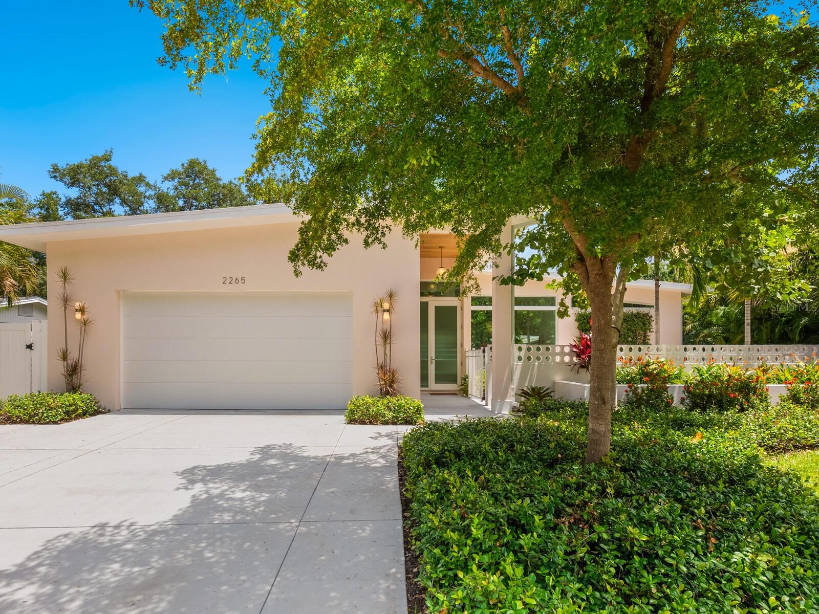 A livable masterpiece in the heart of Arlington Park, this 2021 Markley Construction custom home, designed by renowned firm Architura, is a striking fusion of mid-century modern architectural brilliance and Scandinavian sensibility. Crafted as a piece of art you can live in, every inch of this residence reflects the owners’ unwavering dedication to thoughtful design, natural light and uncompromising quality. Soaring ceilings and walls of high-velocity impact glass invite sunshine to pour through the open four-bedroom, three-bath floor plan, which includes a dedicated pool bath, an oversized two-car garage and a sun-kissed front patio that takes full advantage of the southern exposure. Inside, the home showcases stone countertops and year old high performance wood laminate floors throughout, high-end designer wallpaper, tile, custom window treatments, built-ins and wood tongue-and-groove ceiling detail. Solid core 8-foot doors enhance the architectural integrity, while carefully curated landscaping frames the home with understated elegance. An array of paid off solar panels provides extremely low cost electricity to the home all year long. Solid block construction offers lasting strength and tranquility, and an oversized heated swimming pool with sun shelf and spa framed by clean modern lines completes the picture of refined Florida living. In the sought-after Arlington Park neighborhood in the City of Sarasota, just east of the Trail, this home enjoys proximity to a vibrant community park offering a playground, tennis courts, basketball courts, recreation facilities and a public pool, ideal for active lifestyles and family fun. You’re just minutes from Sarasota Memorial Hospital, the charm of Southside Village, the cultural energy of downtown Sarasota, and the world-class beaches of Siesta Key and St. Armands Circle. Bold yet serene, fortified yet graceful, this is a home that speaks to those who appreciate beauty, simplicity and timeless design.