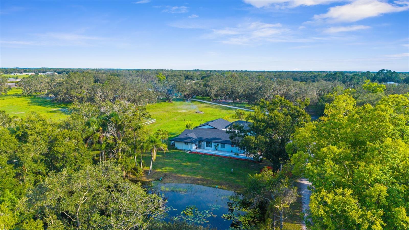 How about 10 Acres and a home of fully renovated beauty! Bring your entrepreneurial spirit to this country setting and flag shaped lot The fully fenced enclave is currently being used as a nursery and horse boarding facility, and sits off SR 64 E. with a private entry road and automatic gate. Drive up to the fully renovated 3100+SF main house with a peaceful pond in front and 3 car garage with additional storage to the side. The air conditioned main areas of the home are large and open - perfect for gatherings of any size. Brand new kitchen is extremely functional and includes soft close cabinets and drawers and a super pantry. A fabulous fireplace wall with TV above graces the gathering area. The home also encompasses 4 large bedrooms- each with its own walk-in closet (wait until you see the primary bedroom closet!) and 3 baths, The main house has 2 new A/C units (4 ton and 2 ton) , 2 zones with all new ductwork in 2018-19. More updates include hurricane impact resistant windows and sliding glass doors installed in 2018. The home features a relaxing screened lanai including a heated pool. And we're not done yet! A Caretaker Bunkhouse also sits on the property. Fully renovated one bed, one bath space has its own kitchen and sitting area with on demand hot water system and new hurricane impact resistant windows. Alongside is a 39’x23’ attached space with 12’ height ceilings and a 16 foot long garage door. All new 200 amp line, new electrical panel. Each living quarters has a generator installed in 2018 and also a 500 gallon propane gas tank for the generators installed in 2019. One well with two water filtration systems and Two septics with 1500 gallon septic tank installed in July 2018. The home and bunk house are being sold completely furnished, tractor and golf cart included! This all includes the advantage of the income and Agricultural exemption from the horse boarding and nursery!
