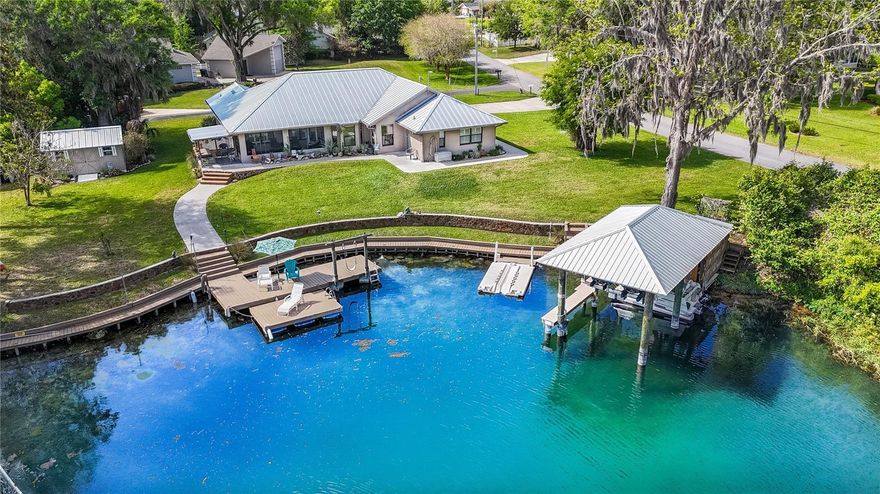 Discover one of the most exceptional waterfront settings on the Rainbow River, where crystal-clear spring-fed waters meet privacy, space, and authentic Old Florida charm. This rare corner parcel offers approximately 200 feet of prime direct river frontage, capturing sweeping panoramic views and refreshing breezes, tucked away from tubers and boaters in a low-traffic corner of the river.

This spacious 4-bedroom, 3-full bathroom home with a 2-car garage features over 2,200 square feet of thoughtfully designed living space. Highlights include a split-bedroom layout, abundant natural light, and a screened rear porch overlooking the river—ideal for entertaining or simply unwinding with breathtaking sunset views.

Key Features & Upgrades:
Approximately 200 feet of prime corner waterfront on the Rainbow River, complemented by expansive decking and multiple dock areas,
New boathouse with boat lift (2021),
New standing seam metal roof (2023),
Concrete seawall,
Granite countertops in the kitchen,
Large backyard shed for additional storage,
Whole-home central vacuum system,
Attached 2-car garage,
River-fed irrigation system,
Floating dock,

Step outside to your private waterfront oasis, complete with a newer covered boathouse and boat lift—ready for effortless days on the water. This peaceful stretch of the Rainbow River is in a protected no-wake zone, creating a mirror-like surface perfect for swimming, paddleboarding, kayaking, and floating right from your backyard.

Enjoy a rare and inviting water entry experience with a shallow wading area along the shoreline that gradually transitions to deeper water—ideal for all ages. Multiple access points include a ladder from the dock and a fun seat swing for an unforgettable entry into the river.

The water maintains a constant 72 degrees year-round, with pristine clarity that makes it feel like your own private natural spring. Enjoy a cleaner swimming area with a built-in river-fed dock system that gently pushes away floating debris—just turn the spigot, no effort needed.

Lifestyle & Location:
Nestled in the desirable Blue Cove community, this golf cart-friendly neighborhood features a low, non-mandatory HOA of just $100 yearly. Residents enjoy access to a private community park and a dock with boat ramp.

Located within city limits in a quiet, tucked-away setting with paved streets, the property has no minimum lease restrictions—making it an excellent choice for a full-time home, vacation retreat, or income-producing investment.

The unique peninsula-style positioning on this corner lot delivers enhanced privacy and expansive water views, creating a rare sense of openness. With recent waterfront upgrades, this home offers the perfect blend of a private oasis and exceptional positioning on one of Florida’s most iconic spring-fed rivers.

Live the Rainbow River lifestyle from your own backyard—an exceptional blend of rarity, tranquility, and unmatched natural beauty.