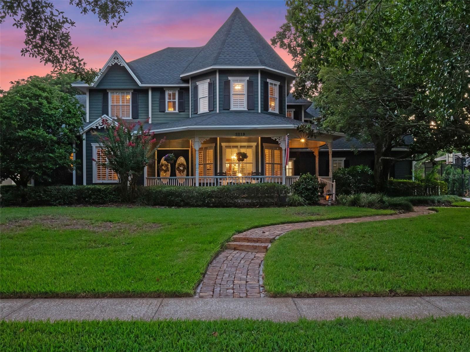 Nestled within the gates of The Estates at Windermere—a community of just 67 homes known for its oak-lined streets and quiet elegance—this Victorian jewel balances architectural romance with modern-day practicality.
The home’s exterior tells a story of timeless design: a turret, wraparound porch, and intricate trim details that feel lifted from the pages of Southern Living. Step inside and you’re welcomed by soaring ceilings, streams of natural light, and finely crafted millwork that frame each space with understated grandeur.
At the heart of the home, the kitchen blends character and utility with rich wood cabinetry, stainless steel appliances, and a gas cooktop—all designed for both the seasoned chef and the casual entertainer. Formal and informal gathering spaces flow seamlessly, anchored by a fireplace that underscores the home’s warmth and charm.
The primary suite, located on the main floor, is a sanctuary of its own, boasting a newly refreshed bath with spa-worthy finishes. An additional downstairs bedroom—currently used as an office—offers flexibility for work or guests, while upstairs you’ll find four more bedrooms. In total, the home provides six bedrooms and three-and-a-half baths, creating room for every need.
Outdoor living unfolds across the home’s rare .63-acre setting. A front porch swing invites quiet morning coffee, while the rear of the property reveals a saltwater pool surrounded by lush landscaping, offering a private retreat reminiscent of a boutique resort.
Living here means more than owning a beautiful home—it means belonging to a serene, gated community just minutes from top-rated public and private schools, premier hospitals, upscale shopping, dining, and Orlando’s world-renowned attractions.
2219 Ridgewind Way is not just a residence; it is a rare opportunity to own a piece of architectural poetry, lovingly updated for modern life, in one of Central Florida’s most sought-after enclaves.