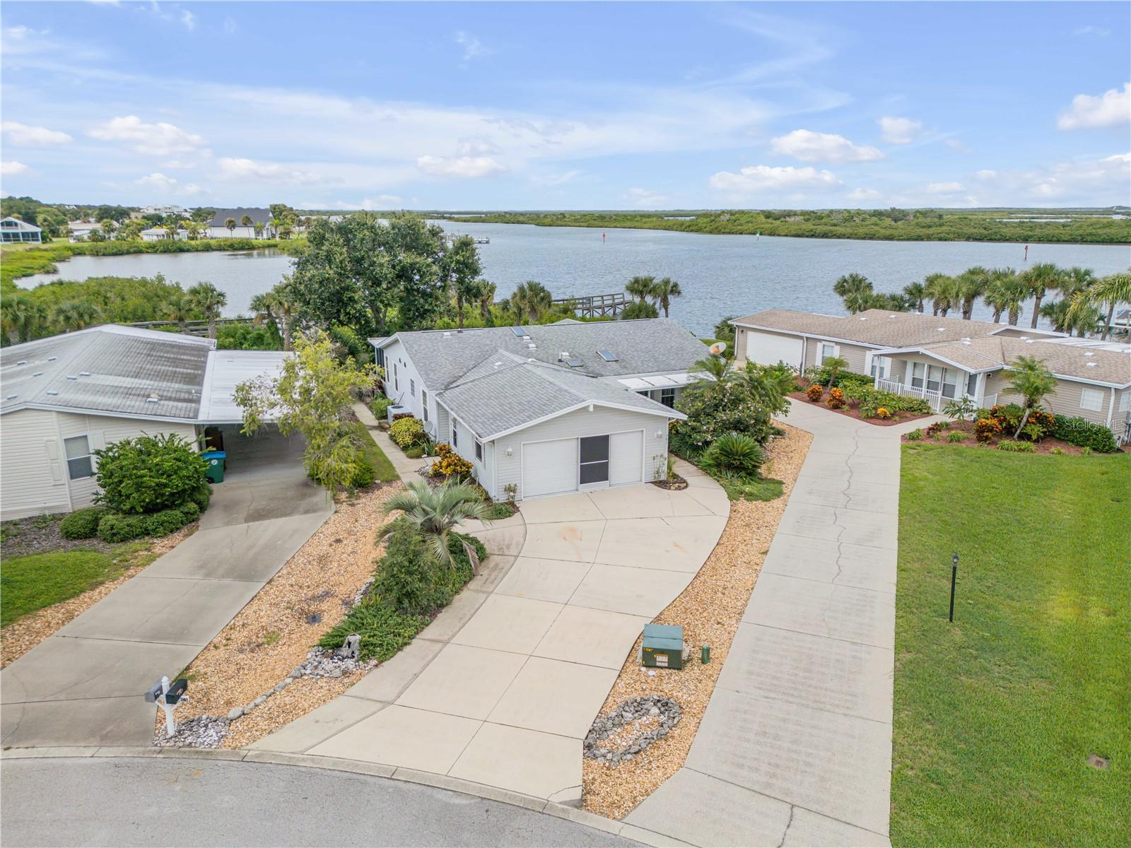 Experience the best of Florida waterfront living in this charming 3-bedroom, 2-bath, home nestled directly on the Intracoastal Waterway, located within the peaceful and friendly 55+ gated community of Lighthouse Cove. This inviting neighborhood features a mix of well-maintained manufactured and block homes, offering a welcoming and relaxed coastal lifestyle. Step inside to find an open floor plan with vaulted ceilings and abundant natural light throughout. The updated kitchen and bathrooms add modern comfort, while the spacious primary suite and generously sized guest rooms offer ample closet space. Both the living area and primary bedroom open onto a large screened-in back porch, perfect for enjoying the surrounding wildlife and tranquil boating views. Additional features include an indoor laundry room, generous sized office space, a two-car garage with an electric RV hookup, and recent updates such as a new roof (2019), oversized AC unit (2020–2021), water heater (2025), and newer stainless steel appliances (2024). Community amenities include a pool, tennis courts, clubhouse with pickleball, and even a boat dock and launch area. With homes in this sought-after community rarely available, now is the perfect time to bring your golf cart and embrace Florida living at its finest! Schedule your showing today!
