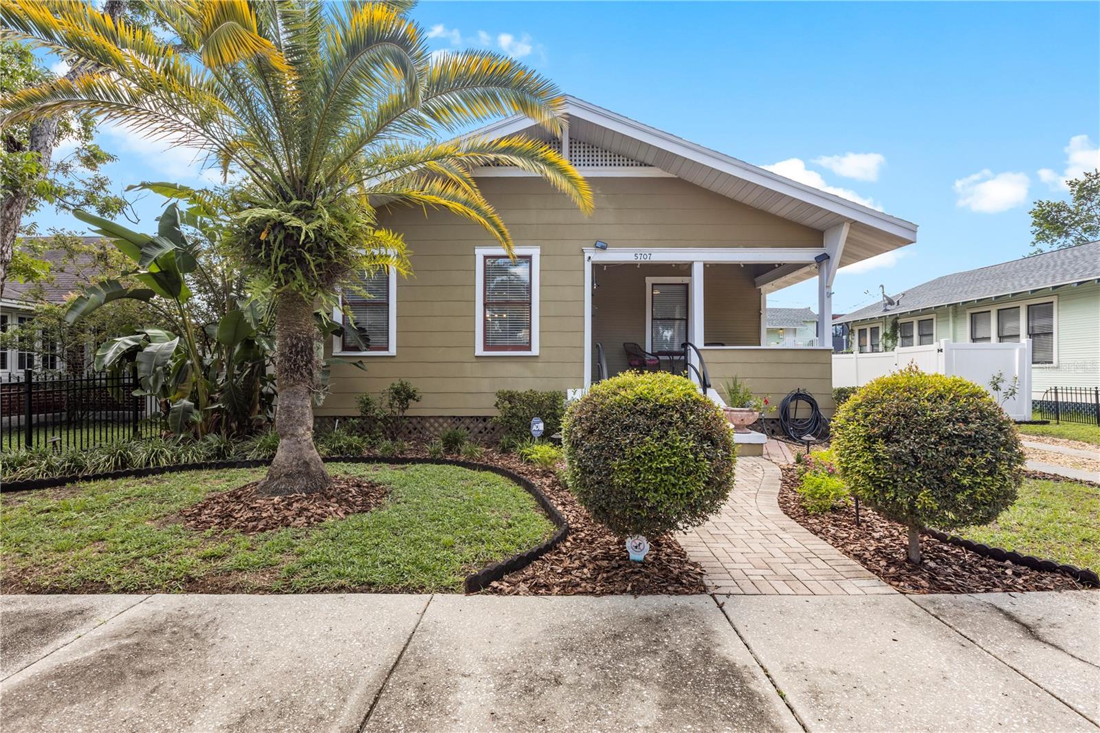 Welcome to this stunning 1922 "Sears Roebuck" bungalow in the heart of Old Seminole Heights! Bursting with historic charm and modern updates, this home features original hardwood floors, leaded glass windows, picture rail, built-in bookcases, and a cozy wood-burning fireplace. The spacious layout offers a bright living and dining area, a guest bedroom with adjacent bath, and a sunlit primary suite with a walk-in closet and en suite bath. The kitchen includes white cabinets with glass doors, stainless steel appliances, and a gas range, with indoor laundry nearby. A sunroom with Saltillo tile flooring and a ductless air conditioner makes the perfect office, den, or craft room. Outside, enjoy the private fenced yard with irrigation and the rare expanded two-car garage. Major updates include a 2020 roof, 2013 gas water heater, and 2006 HVAC. For added peace of mind, the seller is transferring a Select Home Warranty (through Aug. 2026) covering appliances, HVAC, plumbing, and electrical. Conveniently located near I-275, Seminole Heights’ favorite restaurants and shops, downtown Tampa, Busch Gardens, and world-class beaches—this bungalow truly has it all!
