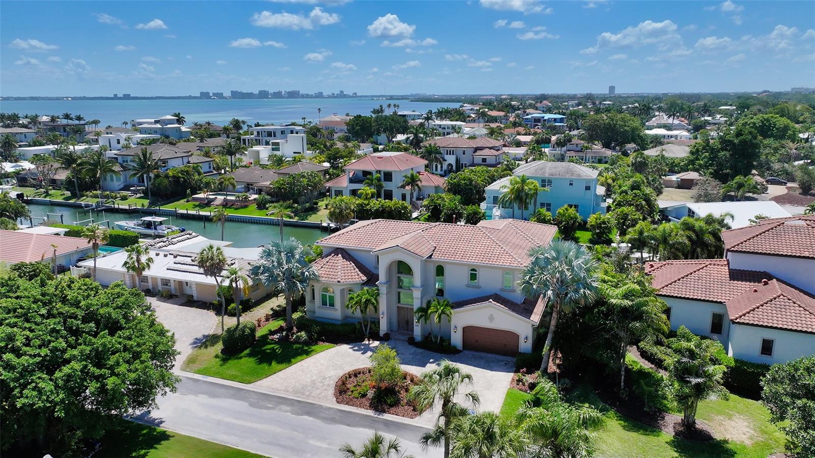 Enjoy an exceptional lifestyle at this coveted Country Club Shores canal home ideal for boaters and less than three blocks from the beach. With direct access to Sarasota Bay and within two minutes of open water, this stately elevated waterfront villa is an exquisite blend of elegant design and modern coastal luxury. Thoughtfully laid out with an inviting primary suite on the main level and four en suite bedrooms on the second floor, the home features oversized windows and incredible sight lines that showcase beautiful views and abundant natural light throughout. Fully remodeled by Klar and Klar Architects, the interior of more than 4,300 square feet boasts a chic harmony of contemporary and classic styles, with large format porcelain tile floors on the main level, a striking marble feature wall surrounding the gas fireplace, gorgeous light fixtures, crown molding, and coffered ceilings.
Setting the luxurious tone, double paneled oak doors open to a bright entrance foyer with direct views of the waterfront. Beyond the main living room’s stunning fireplace surround, the primary suite enjoys first-floor convenience and privacy, with an elegant tray ceiling and designer lighting, private terrace access, a sizeable walk-in closet, and an enormous bathroom with dual vanities, a hydro-spa soaker tub, and glass enclosed walk-in shower. On the opposite side of the main level, past the central living space that opens to the elevated waterfront terrace, a chef’s kitchen overlooks picturesque canal views through hurricane impact glass sliding doors that fully recess. Premium Thermador appliances include double in-wall convection ovens, a built-in microwave, undercounter wine refrigerator, six-burner gas range, and a paneled double door refrigerator. Adjacent to the kitchen and breakfast nook, the dining area offers ample room to accommodate a table for eight, and a spacious family room is ideally situated to enjoy tv-watching from any perch. The open design of the first floor enables a seamless flow between living spaces and indoor-outdoor areas, ideal for both downtime and entertaining.
Upstairs, the large light-filled landing opens to an enormous secondary family room for additional tv and lounge seating, with fabulous views from an oversized window and terrace. Wood flooring throughout the second floor continues the home’s elevated design, with four en suite bedrooms luxuriously updated and echoing the elegance of the main level with tray ceilings, molding, and beautiful lighting. Two of the suites enjoy direct access to terraces that overlook the pool and waterfront.
Outside, a saltwater pool and spa are surrounded by a manicured tropical landscape, with dense palms offering privacy on either side of the home. The new boat dock includes a 28,000 lb lift to accommodate a large vessel, as well as a lower platform for easily embarking on paddleboards or kayaks. Additional luxuries include a pool-side bathroom and another interior powder room, two-car garage with spacious storage, and - for ultimate convenience - an elevator that serves the garage and both living levels. This home enjoys deeded beach access nearby and is within minutes of St. Armands Circle and the cosmopolitan amenities of Downtown Sarasota. Custom-built in 2013, meticulously maintained, and recently updated, this waterfront home is an exceptional blend of refined style and ultimate coastal luxury.