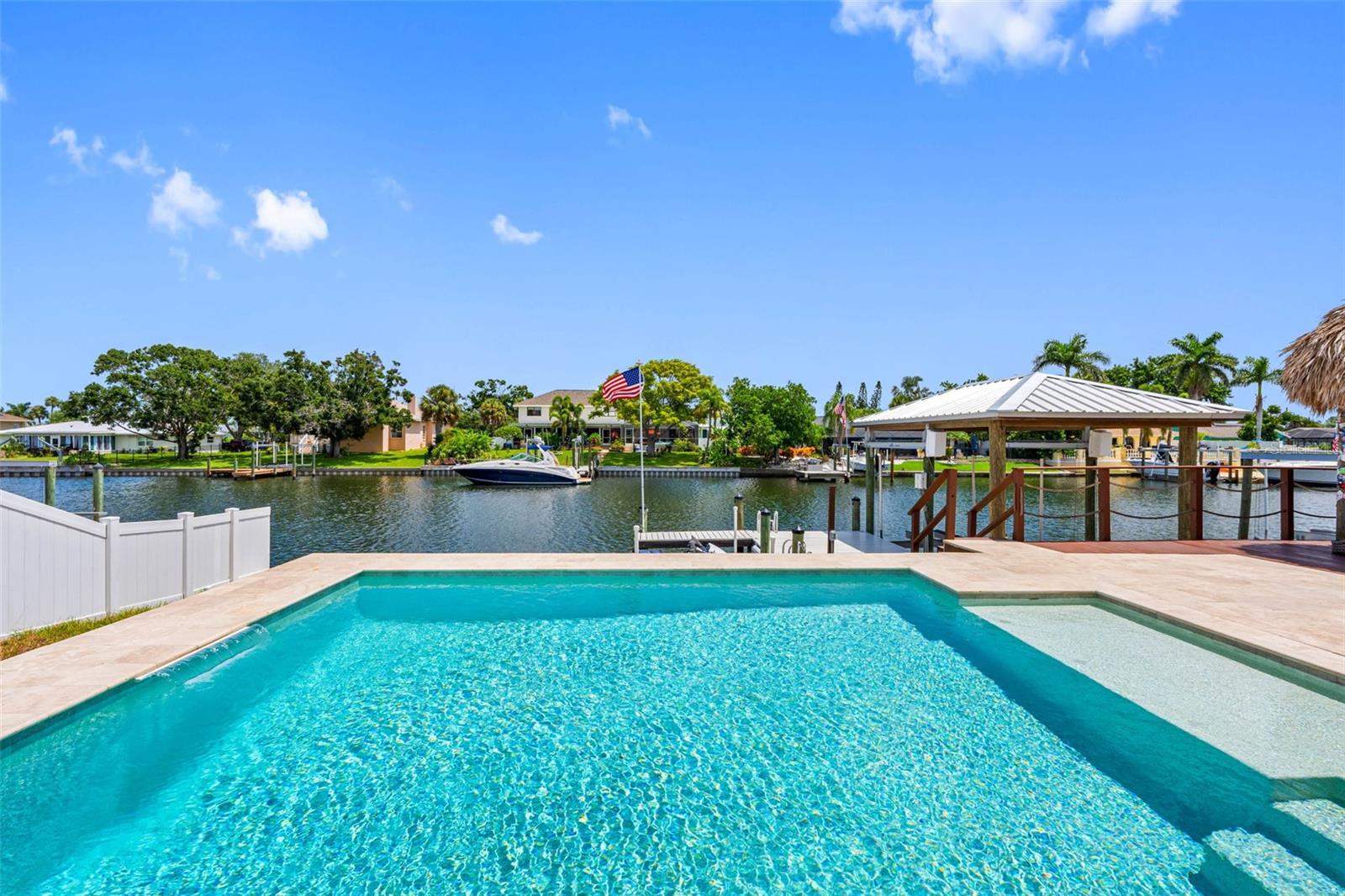 Discover your dream home at 725 Flamingo Dr situated on a deep water canal in beautiful Apollo Beach! This stunning property offers 1680 sq ft with 3 bedrooms and 2 bathrooms, plus an additional air-conditioned converted garage sporting a mini-split A/C providing ample space for comfortable living. Rest easy knowing the home remained high and dry during last year's weather events. Enjoy over 1500+ Sq Ft of outdoor living space with your own private Tiki Bar and outdoor kitchen overlooking breathtaking waterfront views. Relax in the sparkling pool (2019) with a pebble finish, sun shelf and a travertine deck. This home has also been thoughtfully updated throughout with wood look porcelain tile, complete master bath reno, granite counters, fresh interior paint, fixtures, lighting and ceiling fans. Entertaining is a breeze with an open concept, vaulted ceilings and a fireplace. No need to worry about the roof, standing seam metal roof installed in 2023. Newer Trane A/C and electrical panel as well. The seawall was just replaced in 2025, 10K boat lift (2016) and boat roof (2020) oversized driveway (2022). Come experience the vibrant lifestyle Apollo Beach has to offer. Conveniently located to major highways that provide easy commute to Tampa, Orlando, Sarasota and the Gulf Beaches. Interior images with furnishings have been virtually staged.