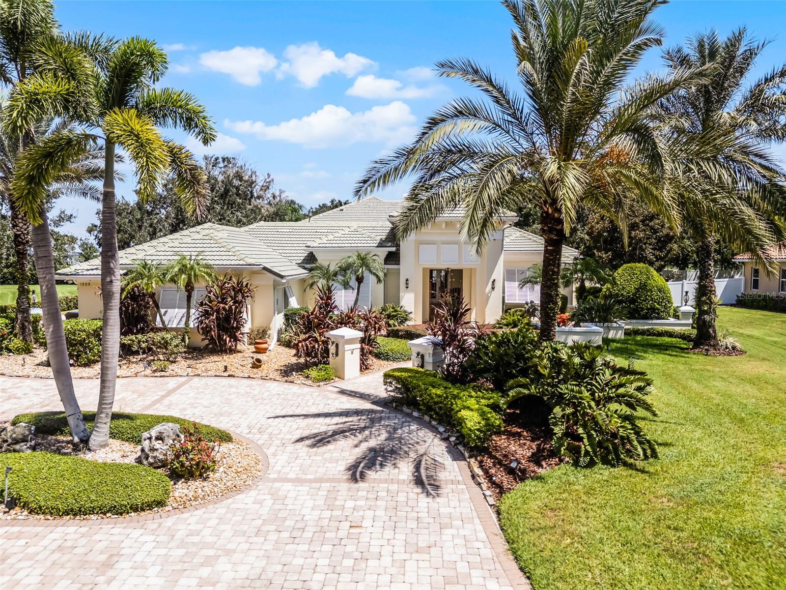 This extraordinary custom estate is located in the exclusive, gated community of Regal Point, set along the shores of Lake Toho. Nestled on nearly an acre (.91) along a quiet, brick-lined street canopied by mature trees and lush landscaping, this meticulously designed residence blends timeless elegance with modern comfort and privacy. A circular paver drive and wrought-iron gated breezeway lead to a serene courtyard entry with a fountain, creating a grand first impression. Inside, soaring 14-foot tray ceilings and travertine marble floors grace the main living areas. The chef-inspired kitchen showcases rich custom cabinetry, granite countertops, a hidden walk-in pantry, center island with pot rack, built-in desk, butler’s pantry, and both over and under cabinet lighting. The adjacent family room features a gas fireplace and built-in surround sound, ideal for relaxing or entertaining. The luxurious primary suite serves as a peaceful retreat, complete with a cozy sitting area and gas fireplace, two spacious California closets—one of which functions as a reinforced safe room, and a spa-style bath with walk-in shower, soaking tub, and tranquil Zen garden view. A richly appointed office with wood-paneled walls and coffered ceiling provides the perfect workspace, while the oversized laundry room includes dual built-in desks, a laundry sink, and a picture window overlooking the lake. A custom theater room offers a 90” screen, 1080/3D projector, surround sound, and soundproof leaded walls. The room is also pre-plumbed for a full bath, making it easy to convert into a guest suite or in-law quarters. Additional bedrooms feature walk-in closets and share a well-appointed Jack and Jill bath. Step outside to a fully screened and heated pool and spa with a 4-foot depth ideal for exercise. The expansive lanai includes multiple seating areas and a fully equipped summer kitchen with grill, cooktop, ice maker, and sink. Beyond the screen enclosure, an open-air paver patio provides the perfect spot for a fire pit or sunbathing. Additional upgrades include a generator supporting the primary suite, office, and kitchen appliances, a water softener system, and reverse osmosis with hot/cold tap at the kitchen sink. Smart home technology, whole-house audio, an alarm system, and coded entries offer convenience and peace of mind. Hurricane protection includes a mix of electronic storm shutters and Bahama shutters, and a mosquito misting system is installed around the perimeter. Designed with accessibility in mind, the home is wheelchair friendly throughout. The 3-car side-entry garage includes one bay converted into a climate-controlled workshop with additional storage. A brand-new A/C unit was recently installed to service all areas except the primary suite and office, which operate on a dedicated system. Don’t miss out on this rare opportunity to own a one-of-a-kind residence with serene surroundings and unbeatable access to everything Central Florida has to offer.
