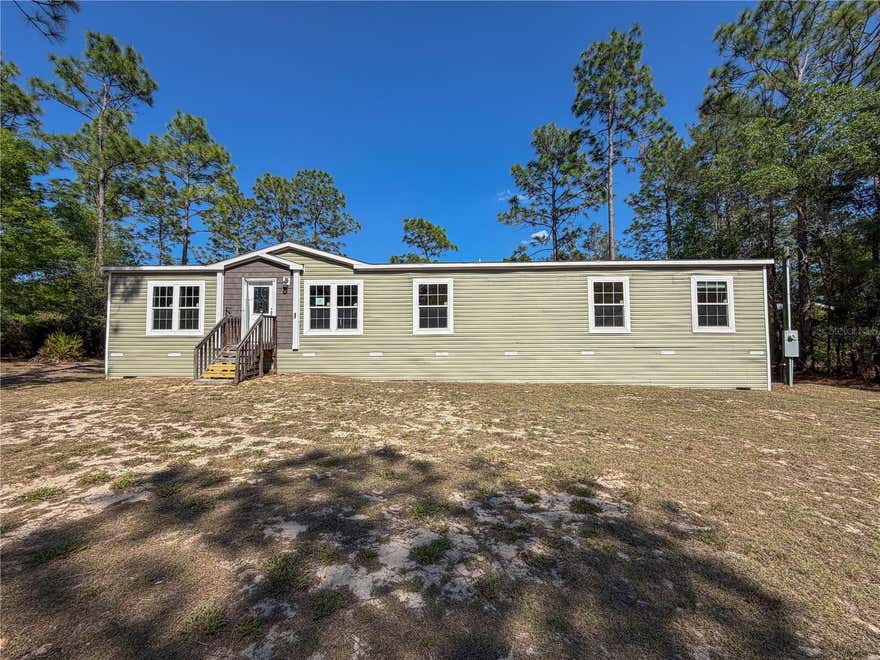 An inviting rural retreat located between Bronson and Williston offers the perfect blend of space and serene surroundings. This expansive 2021 doublewide by Live Oak Homes spans 2,100 square feet and is situated on over half an acre. Inside, you’ll find a thoughtfully designed layout featuring five bedrooms and three full bathrooms, with walk-in closets in four of the five bedrooms. Two separate living rooms offer flexibility for entertaining, relaxing, or creating a dedicated media or hobby space. The heart of the home is the island kitchen, complete with an adjacent dining area ideal for everyday meals or larger gatherings. The spacious primary suite includes a well-appointed bath with dual sinks, a soaking tub, and a separate walk-in shower. The laundry room connects the primary bath and kitchen. Step outside to the rear yard, where peaceful pasture views create a tranquil backdrop. With plenty of space to add a pool, fire pit and/or storage shed,  this property offers endless possibilities to enjoy the quiet charm of country living for the whole family.