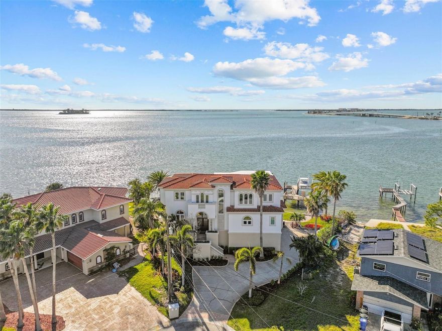 Boasting almost 200 feet of direct, panoramic Gulf frontage, this elegant home has sprawling views that include the Dunedin Causeway bridge! Balmy Gulf breezes and sparkling turquoise waters provide the backdrop for this stunning custom residence, designed by Shoreline Design Group and built in 2000 by Arthur Maxwell & Associates.  Spend your days lounging by the elegant oceanfront pool or hop on your boat and enjoy the open water access; this home offers the best of Florida’s lifestyle. You’ll love the elegant, spacious interiors and well-designed floor plan, with both formal and casual living spaces. The main floor is elevated well above the floodplain and features a grand balcony overlooking the water, the perfect spot to grill out and enjoy the spectacular sunsets! The interiors are well appointed with luxurious finishes and modern conveniences, including an elevator. Entertaining is a joy, with spectacular views from almost every angle, and a custom dry bar appointed in gorgeous marble. The casual spaces are open and inviting, well appointed, and generously sized. The kitchen is a chef’s dream and features granite countertops, solid wood cabinetry, and a thoughtful, well- designed layout including a large walk-in pantry with a dumb waiter.  The bedrooms are located on the top floor, and the primary suite has exceptional views – imagine waking up every morning to never ending vistas! The primary bathroom was recently remodeled and features luxurious marble finishes, with a soaking tub and spa- like atmosphere. Rest easy knowing that this home is very well maintained and also qualifies for insurance deductions/ wind mitigation with impact rated windows, doors, garage doors, a tile roof, and high and dry living areas. Other thoughtful features include a 13,000 lb boat lift, whole house generator, a water softener with filter, jandy pool system, and Sentricon system. Conveniently located just south of the Dunedin Causeway and Honeymoon Island with easy access to the Pinellas Trail, downtown Dunedin, and fabulous amenities, such as golf courses, dining, and recreation, this home offers everything you could dream of!