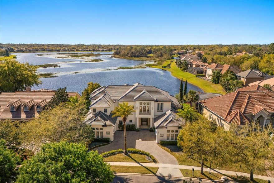 Welcome to 1485 Langham Terrace—a one-of-a-kind custom estate where modern luxury meets serene waterfront living. This architectural masterpiece offers an unmatched blend of style, functionality, and presence, thoughtfully designed with soaring ceilings, sleek finishes, and dramatic natural light at every turn. Upgrades galore, main one being A BRAND NEW ROOF, newer A/C's, new water heaters, new pool heater and more! Upon entering, you're greeted by open, airy volume ceilings, striking steel railings, and a floating staircase that sets the tone for the contemporary elegance throughout. To the right, just past a sleek home office, you’ll find a dedicated pool bath and the primary suite, perfectly positioned for privacy and indulgence.
The primary bedroom is a true retreat, boasting a built-in fireplace, plush carpeting, and a wall of windows that frame stunning pool and water views. Dual windows on either side of the bed add even more light, while soft contemporary lighting and rich accent tones complete the tranquil mood. The spa-like primary bath features a walk-in steam shower with ceiling detail that’s both architectural and artistic, multiple body jets, a sunken jetted tub beneath skylit windows, and a private sauna tucked to the side. Dual vanities and a massive custom closet with sleek cabinetry and organization finish the space with style and functionality. One Car garage conveniently attached to the primary closet!
Back in the main living area, a dramatic formal dining room is perfectly centered beneath double-height ceilings and flanked by designer built-ins. It opens to a butler’s pantry connecting the space to the heart of the home—the modern chef’s kitchen. Equipped with high-end stainless-steel appliances, dual sinks, sleek cabinetry, a wraparound breakfast bar, and an additional island with a custom stainless prep counter, this kitchen blends style and utility with ease.
The kitchen overlooks the spacious family room, designed for comfort and connectivity. Floor-to-ceiling windows and glass sliders invite the outdoors in, showcasing the incredible backyard views, while a sleek linear fireplace and mounted TV anchor the living space in warmth and technology. A stunning centerpiece of the living room, the massive fish tank brings a unique blend of tranquility and elegance to the space. 
Head upstairs via the grand staircase, where you'll find a loft, three generously sized bedrooms, each with its own ensuite bath, and a bonus room perfect for media, play, or a private gym.
Now, lets step outside.
The screen-enclosed patio is a true extension of the living space, featuring a complete outdoor kitchen, multiple seating areas, ceiling fans, and clean architectural columns. It's the perfect setting for alfresco dining, morning yoga, or a quiet evening under string lights.
But the crown jewel of this estate? THE UNMATCHED LAKEFRONT VIEW. A resort-style pool with a sun shelf and spa stretches toward the water's edge, framed by vibrant landscaping and UNOBSTRUCTED PANORAMIC LAKE VIEWS. Whether you're taking a swim or sipping your coffee, the sunrise and sunset dance across the water, turning every moment into something magical. Located in the 24-hour guard gated golf community of Heathrow, this home offers a peaceful pace of life with many amenities for healthy living, such as walking trails, additional sports courts, a soccer field, tennis courts and basketball courts.