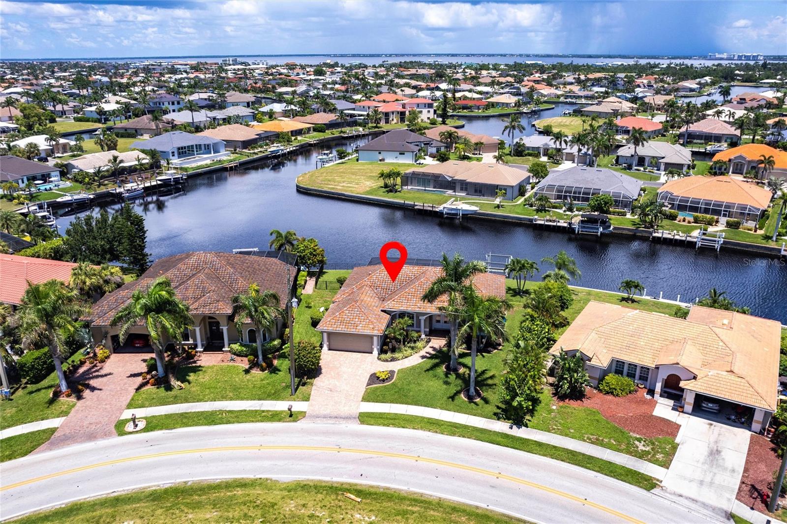 Superb quality and built to perfection, this custom waterfront pool home offers 3 bedrooms, 2 baths and a spacious two-car garage. Nestled in the highly desirable golf and waterfront community of Punta Gorda Isles (PGI), this beautifully crafted residence features 116 feet of seawall, stunning perimeter views, and direct water access to Charlotte Harbor and the Gulf of Mexico. With 2,087 square feet of living space, the home showcases a bright, open, and split-bedroom floor plan designed to maximize natural light and capture tranquil canal views from nearly every room. From the moment you arrive, the lush tropical landscaping, brick-paved driveway, and welcoming walkway create a strong sense of arrival and exceptional curb appeal. Inside, the spacious great room features a dramatic volume tray ceiling, elegant tile flooring throughout, and a formal dining room currently used as an office or sitting area, offering flexibility to suit your lifestyle. Sliding glass doors open the interior to the expansive lanai, seamlessly blending indoor and outdoor living. At the heart of the home is the thoughtfully designed kitchen, featuring granite countertops, a matching tile backsplash, custom wood cabinetry with upper crown molding, a full suite of stainless-steel appliances, and a generous breakfast bar highlighted by stylish drop pendant lighting. The kitchen overlooks the main living area, making it perfect for entertaining or everyday comfort. The split-bedroom layout provides ideal privacy for guests, with two spacious guest bedrooms sharing a full bath—one of which offers direct access to the lanai. The primary suite is a peaceful retreat with views of the pool and canal, private lanai access, a large walk-in closet, and a spa-inspired ensuite bath with a Jacuzzi tub, dual vanities, and a walk-in tiled shower. Step outside to discover a true Florida paradise. The lanai and pool area are the ultimate in relaxation and style, featuring a sparkling heated saltwater pool with a new salt system and pool cage installed in 2023. The paver patio and shaded sitting area invite year-round enjoyment, all set against the backdrop of beautiful water views. Additional highlights of the home include hurricane protection with some impact windows, a dedicated laundry room with storage, extra insulation for improved energy efficiency, updated lighting fixtures, modern ceiling fans, a BS550 generator, Bahama shutters, water filtration system and a fenced pet area. The home is also equipped with a 10,000 lb boat lift with water and electric at the dock. Recent updates include a 2018 HVAC system, 2023 dishwasher, and 2019 washer and dryer. The home sustained no storm damage from Hurricanes Helene or Milton and has a 9'elevation. Ideally located just minutes from Fishermen’s Village, downtown Punta Gorda, the weekly farmers market, local parks, the PGI Civic Association, public library, Publix, and Punta Gorda Airport, this move-in-ready home combines comfort, elegance, and convenience. With its premium location, exceptional features, and spectacular waterfront setting, this home offers the very best of Florida living. **PLEASE ENJOY THE 3D INTERACTIVE VIRTUAL TOUR ASSOCIATED WITH THIS LISTING**