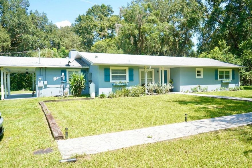 Nestled on over 2 acres in a tranquil country setting, this concrete block home offers serene privacy while still being just minutes from shopping, dining, and The Villages Charter Schools. Tucked back off the road behind a stately oak tree, the property presents classic rural charm.
Step inside to discover a renovated interior with an open-concept layout, including a spacious great room anchored by a cozy fireplace, a dining area, and a light-filled kitchen. The kitchen features tile flooring, stainless steel appliances, granite countertops, beautiful cabinetry, a large sink beneath a picture window, and a breakfast bar with pendant lighting—perfect for casual meals and entertaining.
Throughout the home, warm wood laminate flooring and dark cabinetry.
This home comprises 4 generously sized bedrooms and 2.5 baths, including a master ensuite with a glass-and-tile walk-in shower and roomy vanity. The guest bath continues the granite theme with a square sink and tile-surround tub/shower combo. In addition, there’s a flexible bonus room ideal for use as an office, hobby space, or storage.

Convenience meets smart upgrades with the indoor laundry room coupled with a half bath, offering easy access from the rear of the home. A tankless hot water heater accommodates the household’s needs efficiently.

Outdoors, there’s a concrete patio and covered seating area perfect for relaxing or entertaining guests. A firepit for cooler evenings, plus a charming two-story playhouse tucked into the rear corner, add to the leisure appeal. A recently added 2-car garage, new propane tank, 4-board fencing, upgraded appliances, and a 2018 roof round out the structural and utility enhancements.
Despite its peaceful, private ambiance, this home is well priced and ideally located—close to everything while maintaining a quiet, country lifestyle.

Don’t miss your opportunity—schedule your private tour today!