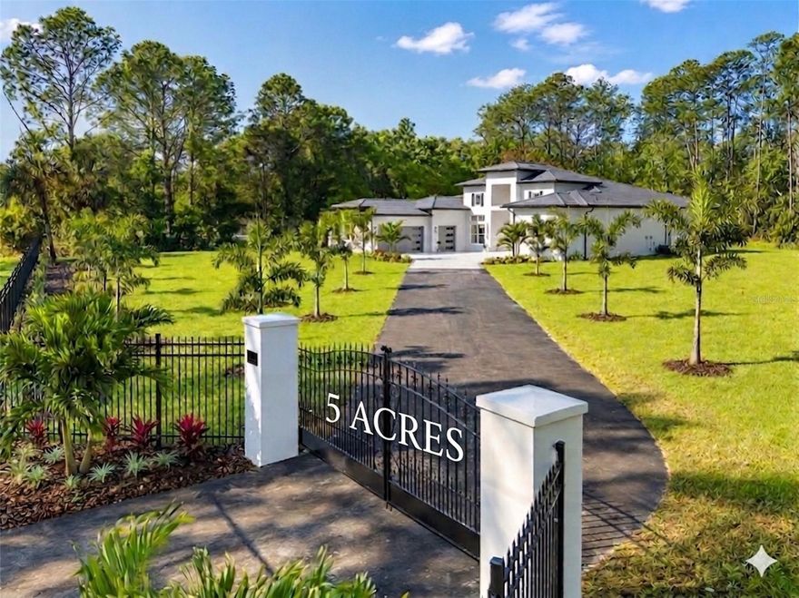 One or more photo(s) has been virtually staged. Back on the Market due to Financing. Brand-new custom-built estate offering 4,179 sq ft of living space (5,558 sq ft under roof) on 5 private acres—never lived in! Ideally located in the sought-after acreage community of Happy Trails, just minutes from Celebration, Reunion, and Walt Disney World, this exceptional property offers the perfect blend of luxury, privacy, and convenience with no HOA restrictions and ample space for horses, recreation, and enjoying your private setting.

Step inside to experience impressive architectural design, highlighted by 24-foot coffered ceilings in the grand foyer and formal dining room, a vaulted ceiling reaching 14 feet in the main living area, and 12–13 foot ceilings throughout, creating a bright, open, and expansive atmosphere.

At the heart of the home is a stunning designer kitchen featuring an oversized island topped with Italian Mona Lisa granite, creating a true centerpiece for entertaining and everyday living. The kitchen is further enhanced by floor-to-ceiling custom cabinetry with illuminated upper display cabinets, a wet bar with wine cooler, and elegant finishes throughout. The open-concept layout flows seamlessly into the main living space, complemented by premium porcelain tile flooring throughout.

The spacious living area features a modern electric fireplace with mantel surround, beautifully complemented by custom built-in cabinetry and designer wall shelving, adding warmth and architectural elegance to the space.

The thoughtfully designed floor plan includes a central living area with a kitchen/family room combo and a desirable split-bedroom layout for added privacy.

The luxurious primary suite is a true retreat, featuring an elegant double-door entry and dual oversized walk-in closets, including a custom “hers” closet measuring approximately 20’8” x 5’6” and a generous “his” closet at 13’8” x 5’8”, both designed with quality wood shelving and mirrored sliding doors.

Additional highlights include Energy Star® certified windows, step-free access throughout, and a beautifully finished paver driveway, walkways, and outdoor living areas. The home is also equipped with a private well system, providing a reliable water source and eliminating monthly water utility costs.

This rare 5-acre estate offers exceptional privacy and space while being conveniently located near world-class dining, shopping, and entertainment.